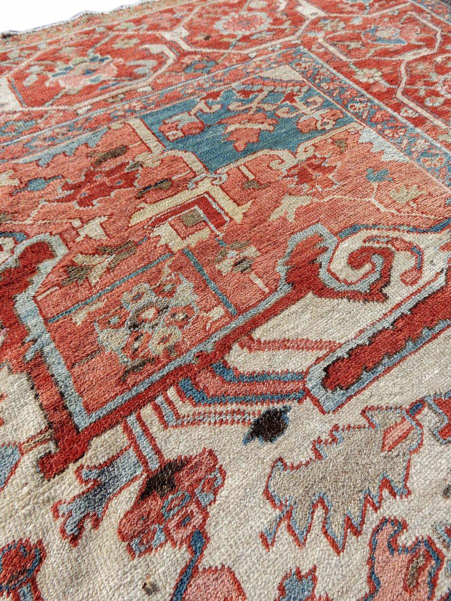 This grand Serapi carpet from the Heriz district of Northwest Persia draws an elegant central lobed medallion, formed from several palmette types, against an ochre red ground. Blossoming networks of vine scroll fill the field, imbuing it with a