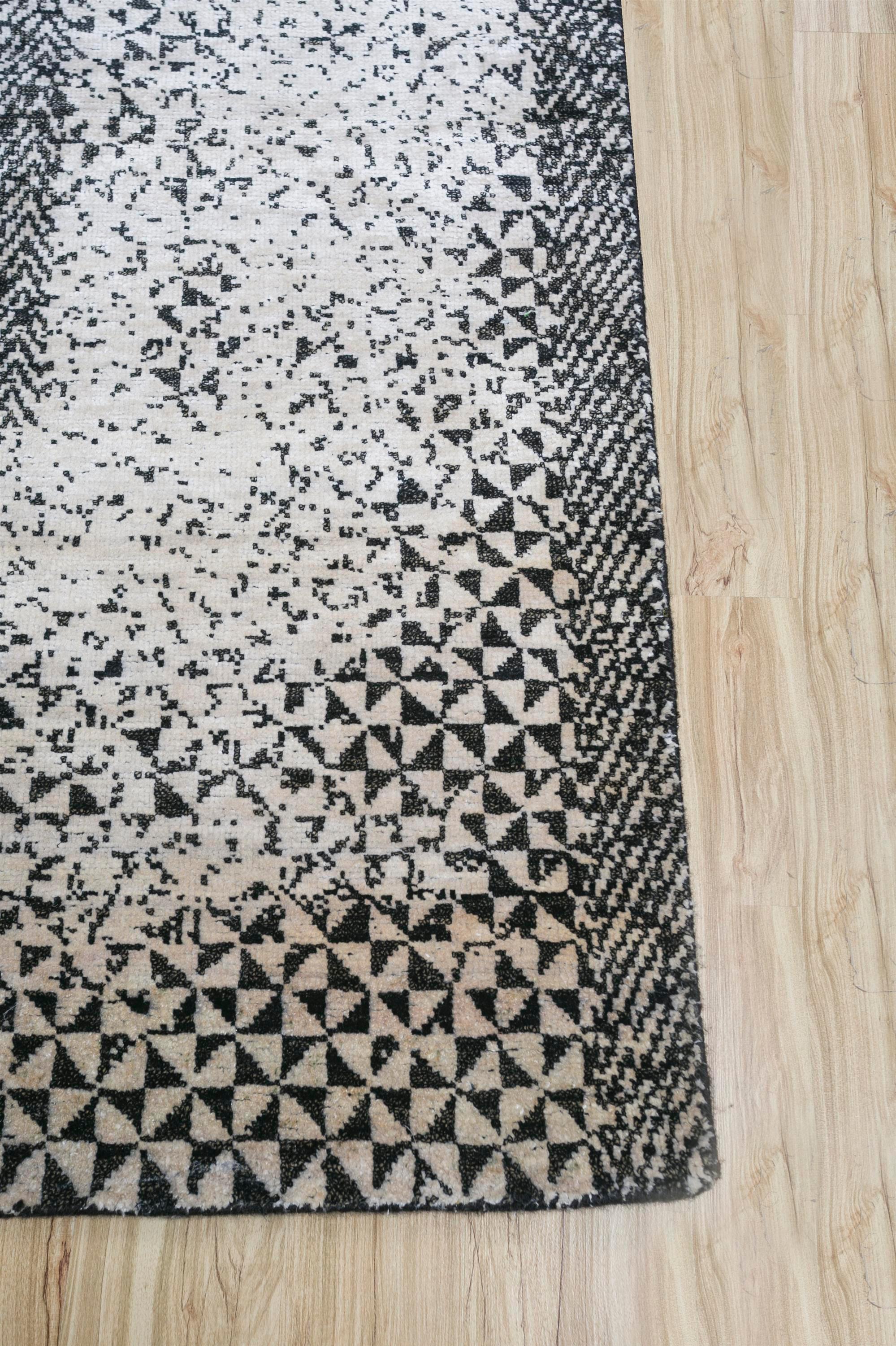 Immerse your space in the elegance of this modern hand-knotted rug meticulously crafted in rural India. With a soothing tone-on-tone palette, this rug effortlessly uplifts the mood of any space. The white ground and ebony border create a canvas that
