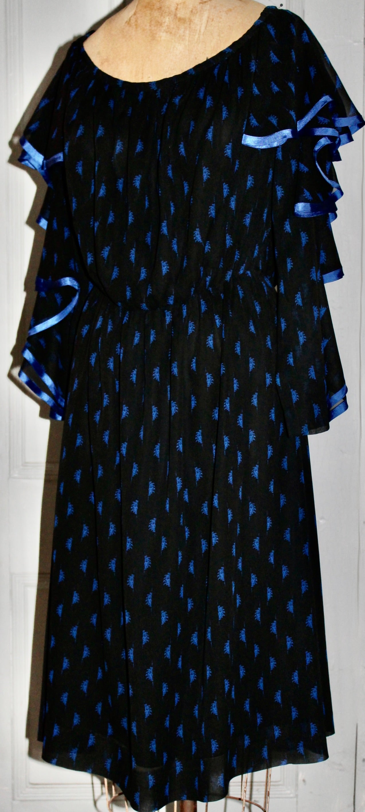 Ein schwarzes Cocktailkleid aus Seidenkrepp mit mehrlagigen Ärmeln, die mit einem zickzackförmigen hellblauen Seidenband verziert sind. Lepage war von 1977-1979 Designdirektor für Schiaparelli und
fünf Haut Couture Collections geschaffen.  Dieses