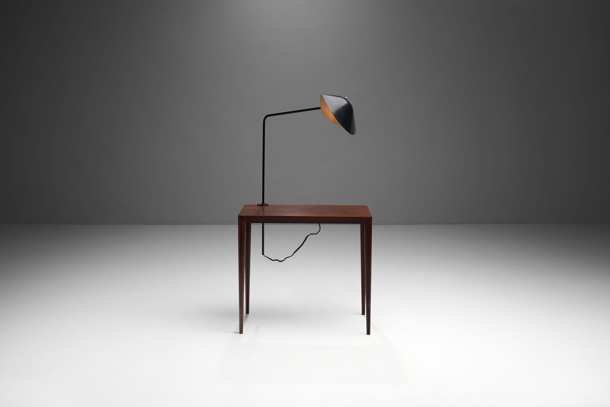 The 'Agrafée simple' desk lamp was designed by Serge Mouille in France, 1957. This clean and timeless Classic of modern design has a black steel structure and an aluminum shade with a black lacquer coating, which is folded into an organic conical