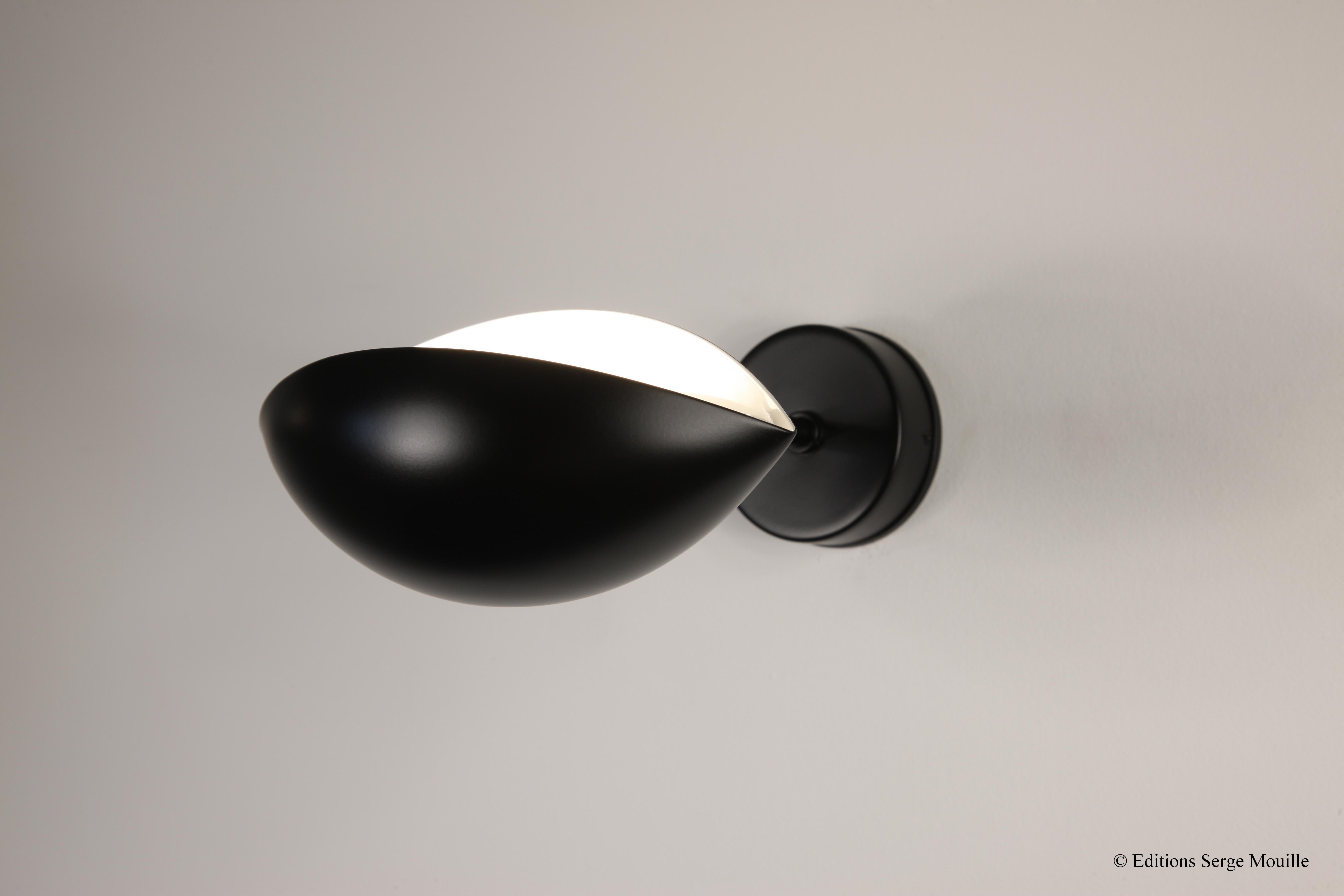 Serge Mouille 'Oeil' wall lamp in black.

Originally designed in 1956, this iconic wall sconce is still made by Edition Serge Mouille in France using many of the same small-scale manufacturing techniques and scrupulous attention to detail,