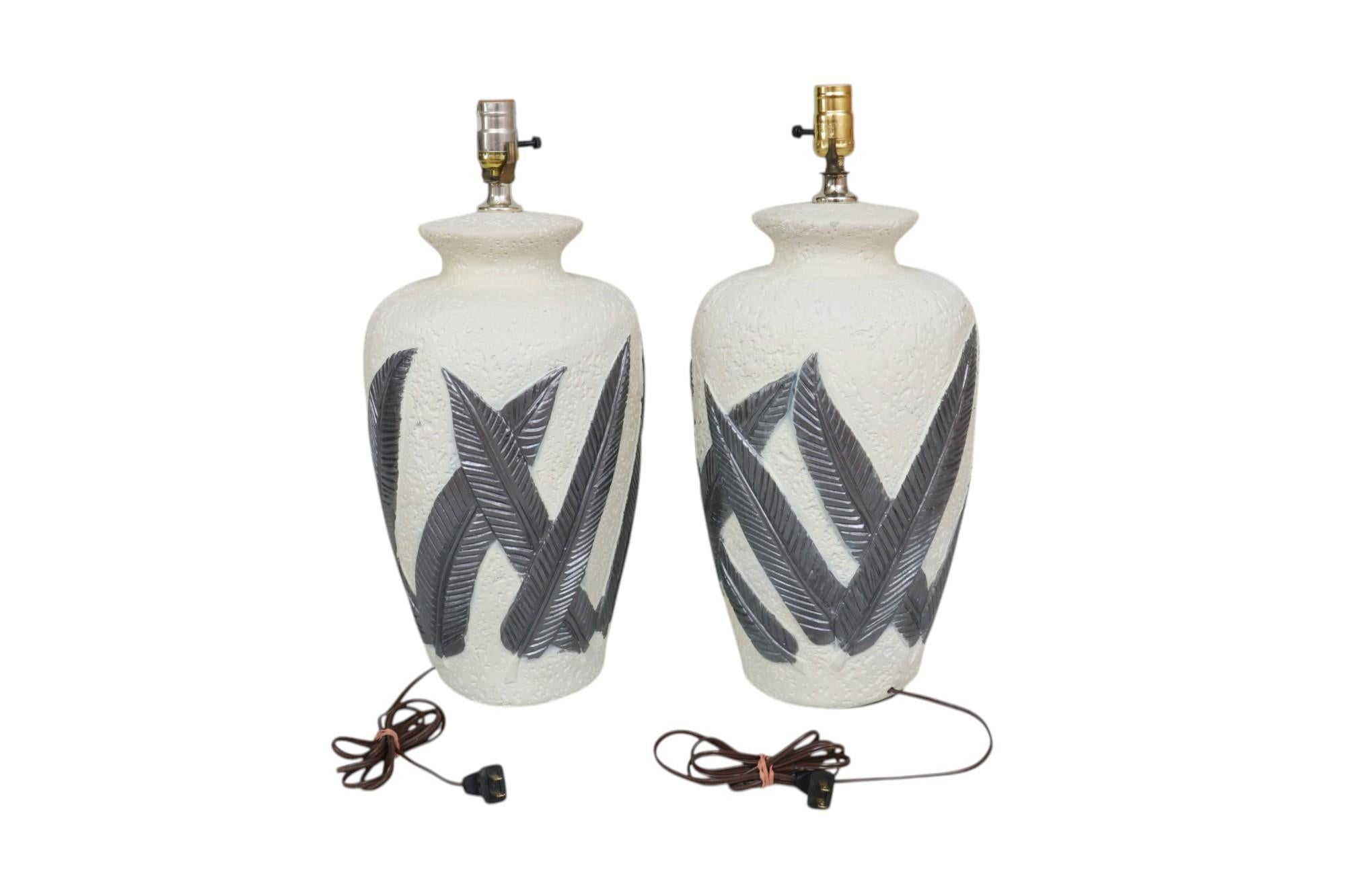 A pair of postmodern ‘banana leaf’ table lamps attributed to Serge Roche. Plaster vases are pressed to give the look of earthenware and are decorated with overlapping hand-painted banana leaves finished in a metallic gray. Dimensions per lamp.
