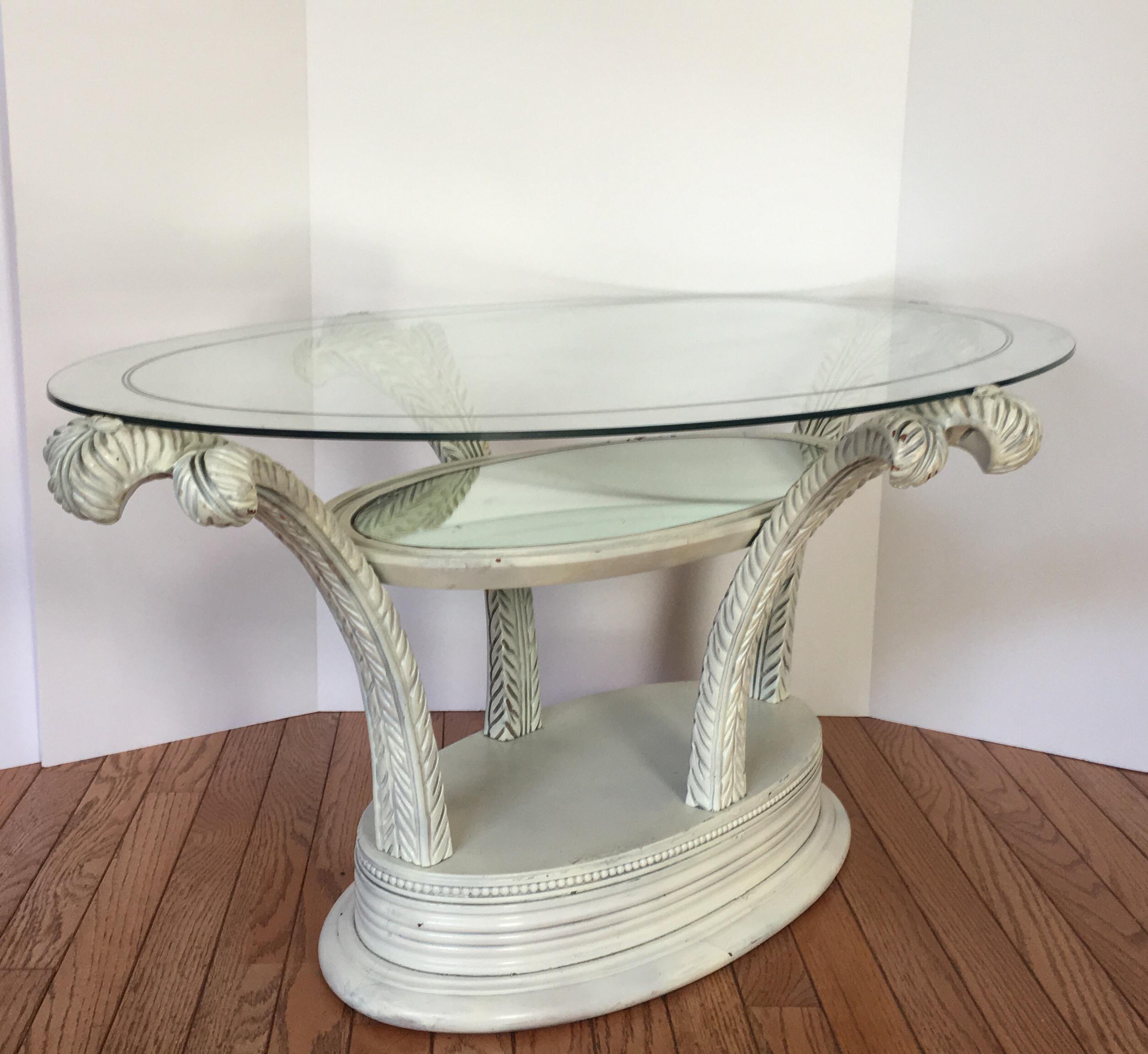 Glamorous Hollywood Regency sculptural coffee table featuring hand carved plumes or palm tree fronds. This occasional cocktail table has three tiers. The lowest tier is the wooden base and can house small knick knacks. The middle tier has original