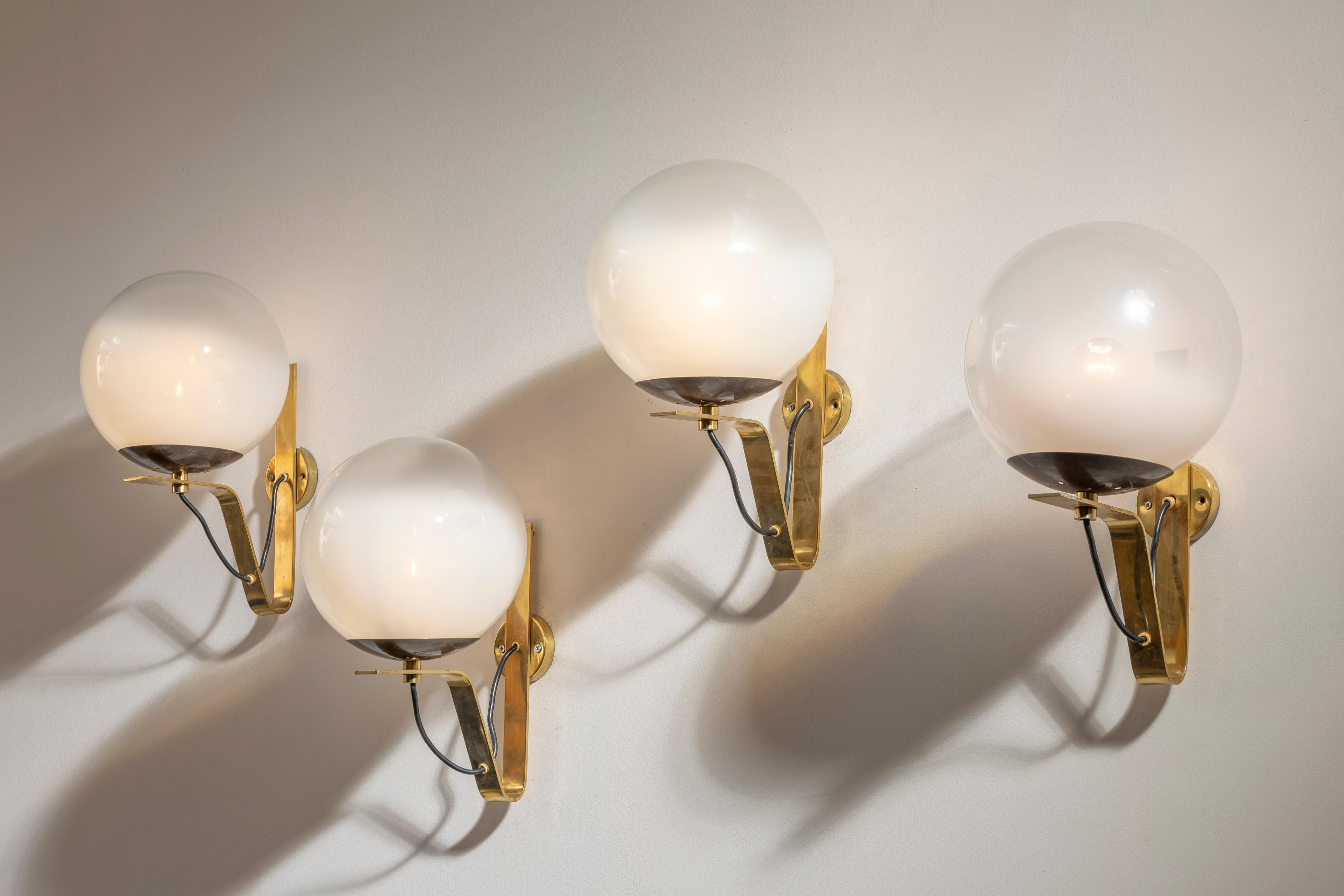 Group of four brass wall lamps, glass, designed by Sergio Asti, model b464, produced by Candle, Italy, 1960. Offered in two sets of two lamps each.

A delicate shaded glass sphere showcases the meticulous design of a series of wall lamps designed by
