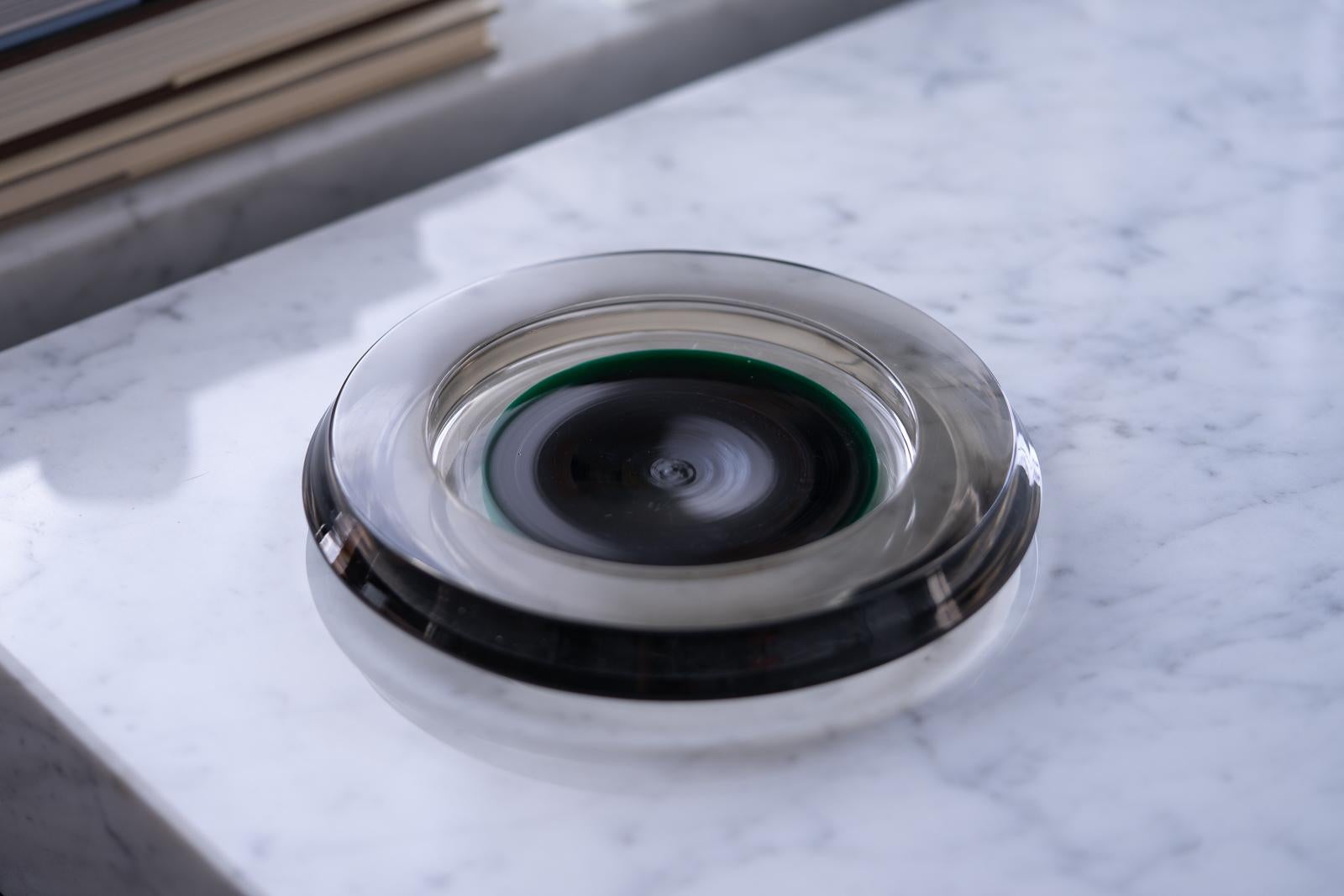 A large, beautiful, low blown glass dish designed by Sergio Asti for Salviati in 1964. The smoke grey body surrounds a deep green center at its core. Tapered sides make it appear to hover above the surface. Incised 