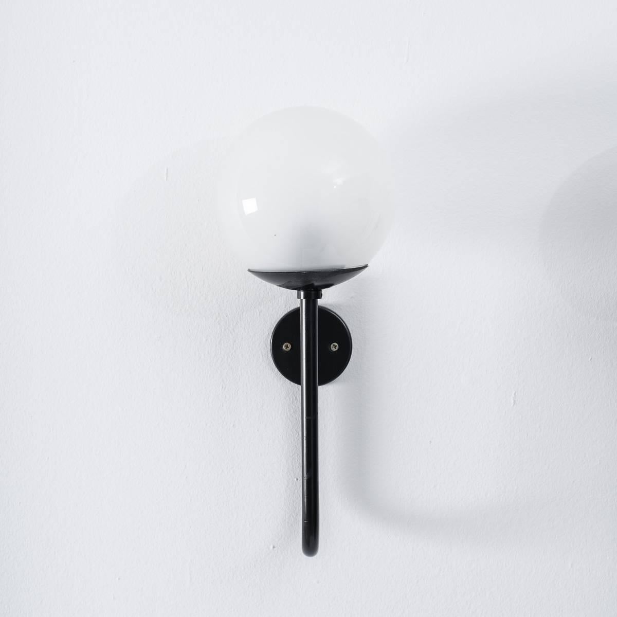 These are a striking pair of wall lights by the prominent Italian architect Sergio Asti for Arteluce. They are formed from a simplistic line created through bent and painted steel. This is crowned with an opaline spherical shade that sits