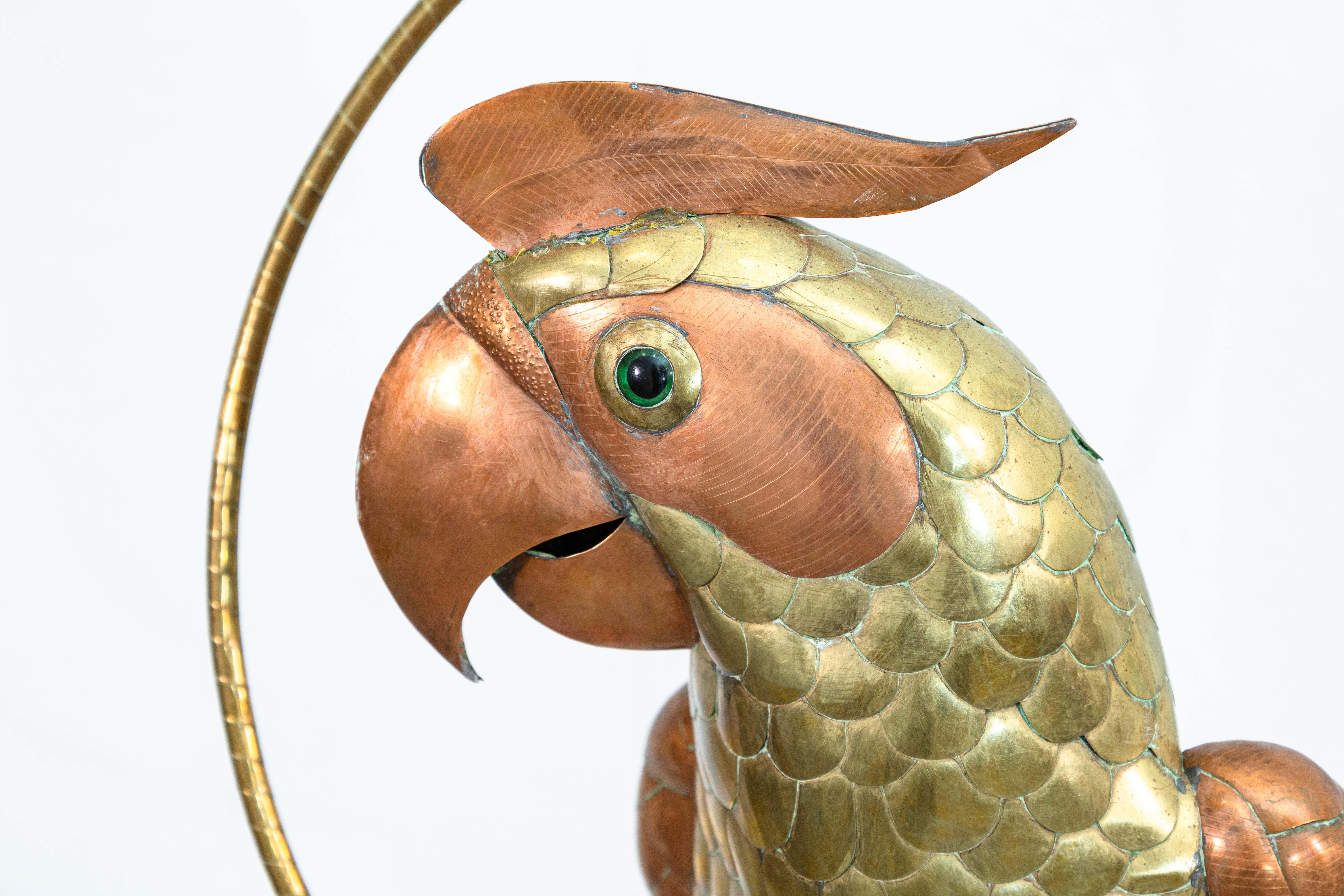 Eine hängende Papageienskulptur von Sergio Bustamante. Diese wunderbare, verspielte Metallskulptur besteht aus Schichten von Kupfer und Messing. Dieses Stück besteht aus dem großen Papagei und der runden, hängenden Sitzstange, an der der Papagei
