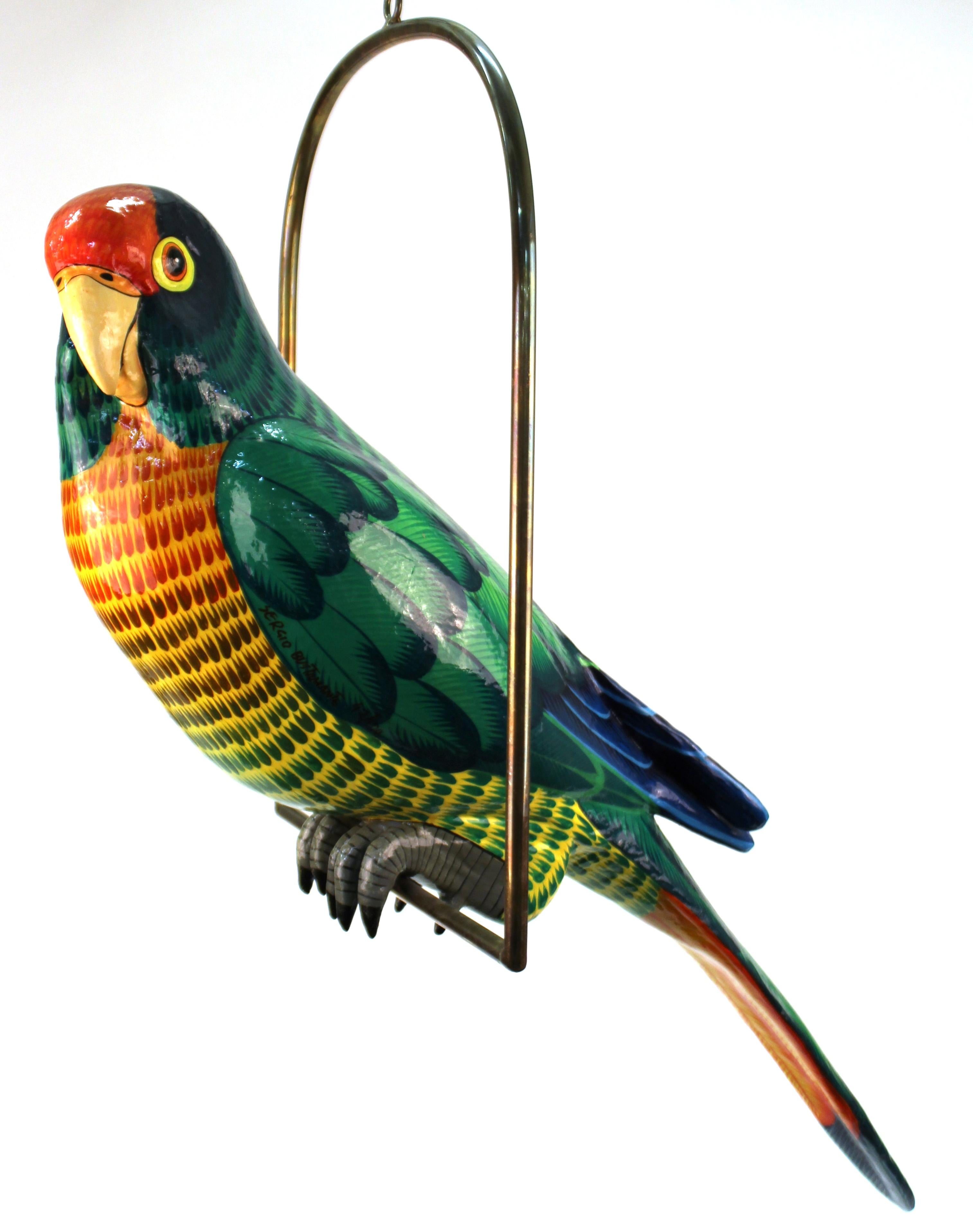 Modern paper mâché hand painted parrot sculpture by Sergio Bustamante, perched on a brass swing. The piece is signed and numbered 42/100 on the side and is in great vintage condition with some age-appropriate surface cracquelure on the parrot.