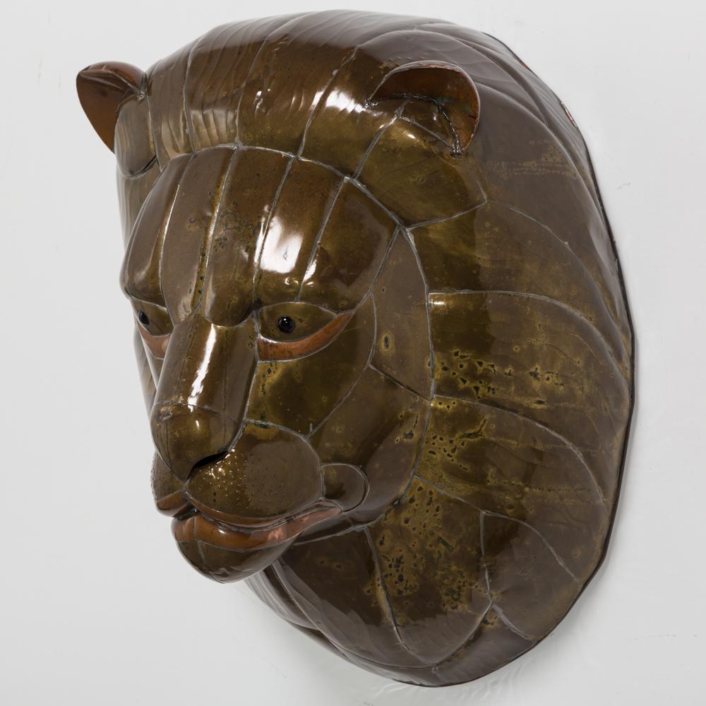 Sergio Bustamante patinated brass lion wall mask sculpture with copper detailing, Mexico 1960s. 

Sergio Bustamante is a Mexican Artist and sculptor. He began with paintings and papier mâché figures, inaugurating the first exhibit of his works at