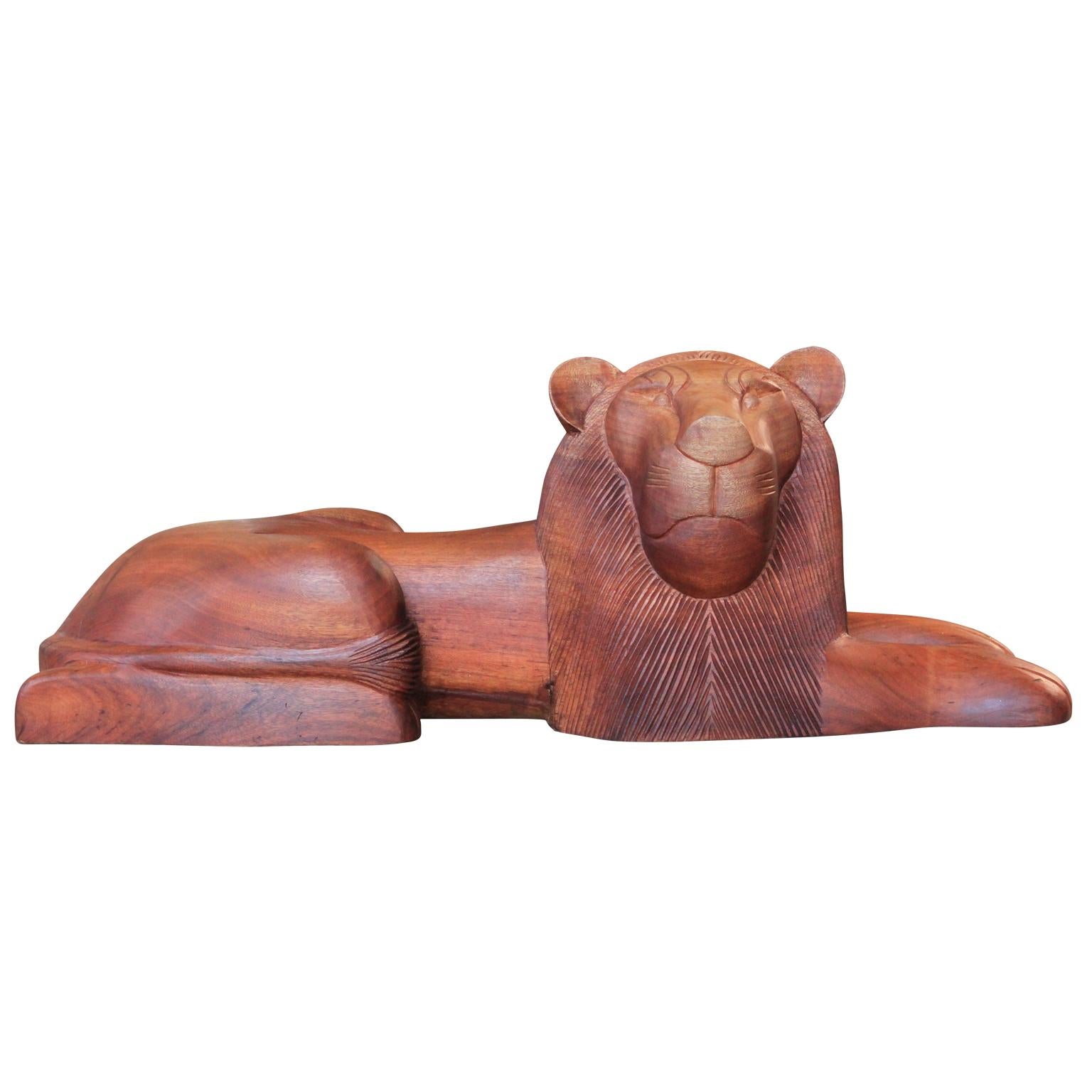 Pair of stylized mid century modern solid teak lion sculptures in the style of the work of Sergio Bustamante. The pieces feature a smooth, polished finish with intricately carved facial details. Signed 