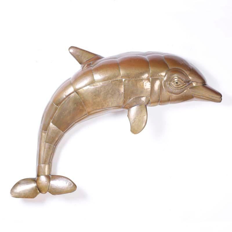 Sculpture de dauphin en laiton martelé à la main, pris en plein saut avec une expression amicale familière, attribuée à Sergio Bustamante. Conservant sa patine et laqué pour un entretien facile.