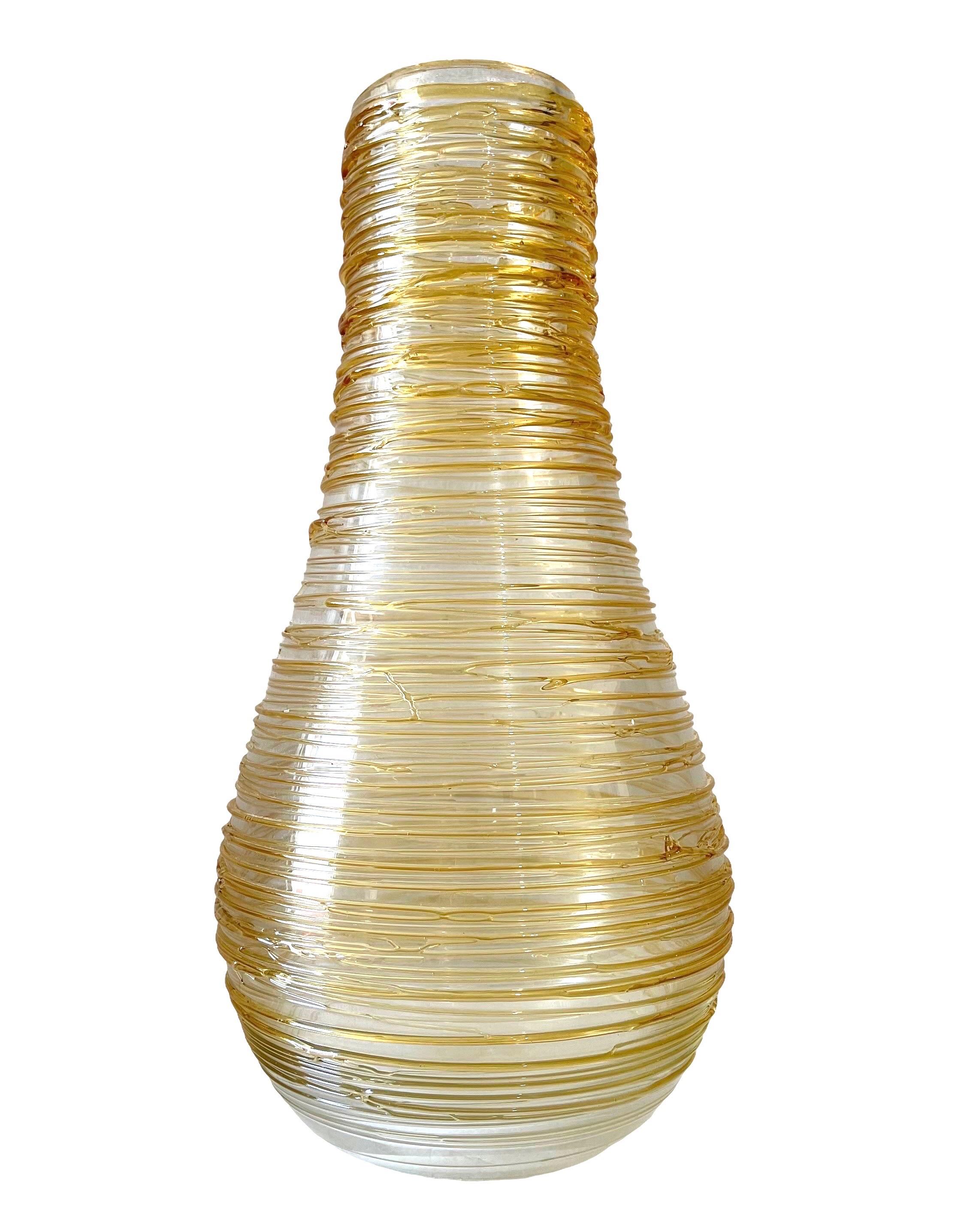 

Dimensions: 15.5 X 7 X 7 in. 
The organic shaped vase showcases an applied light gold colored threaded design enveloping the clear body, around. Hand signed Constantini S. It came from an important estate in the Palm Beach area.
Made in Murano,