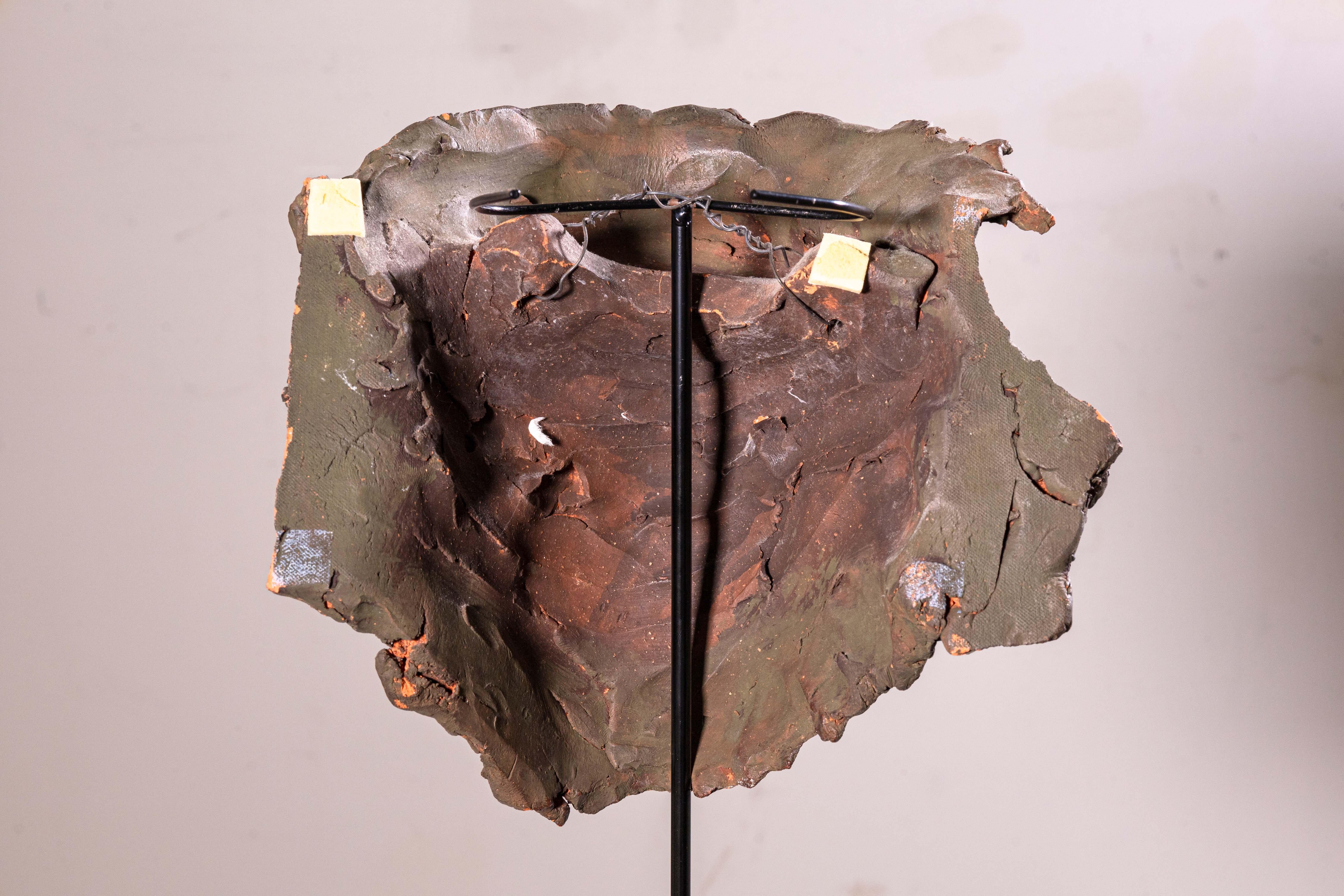  A modernist contemporary painted ceramic sculpture depicting a biomorphic face or mask-like form by Detroit artist Sergio De Giusti. A fascinating composition where the face seems to emerge from an abstracted form. Displayed hanging on a minimal
