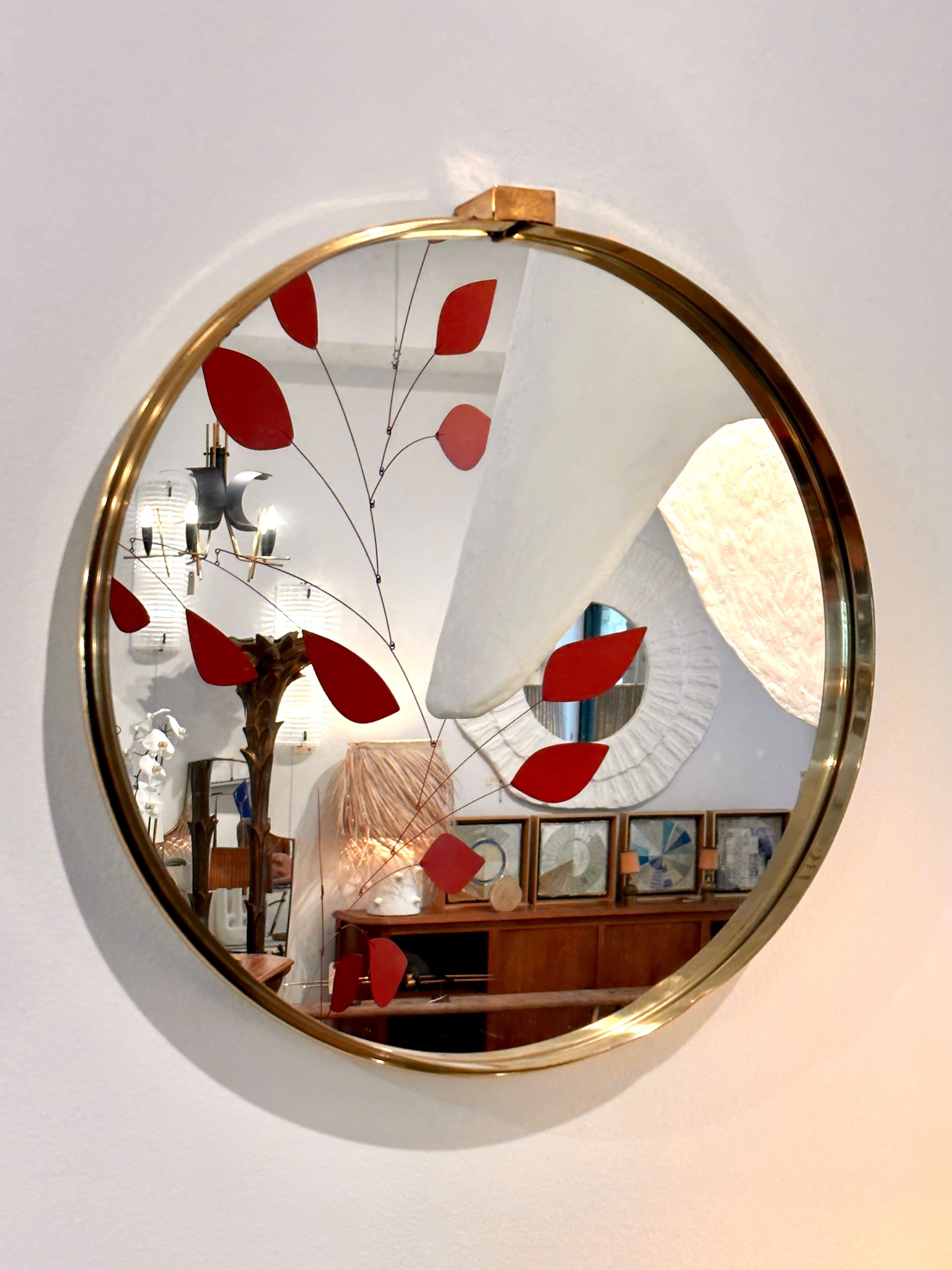 This round mirror features a thick brass strap trim surrounding the glass with a buckle at the top.  Very quality and heavy mirror.  THIS ITEM IS LOCATED AND WILL SHIP FROM OUR EAST HAMPTON, NY SHOWROOM.