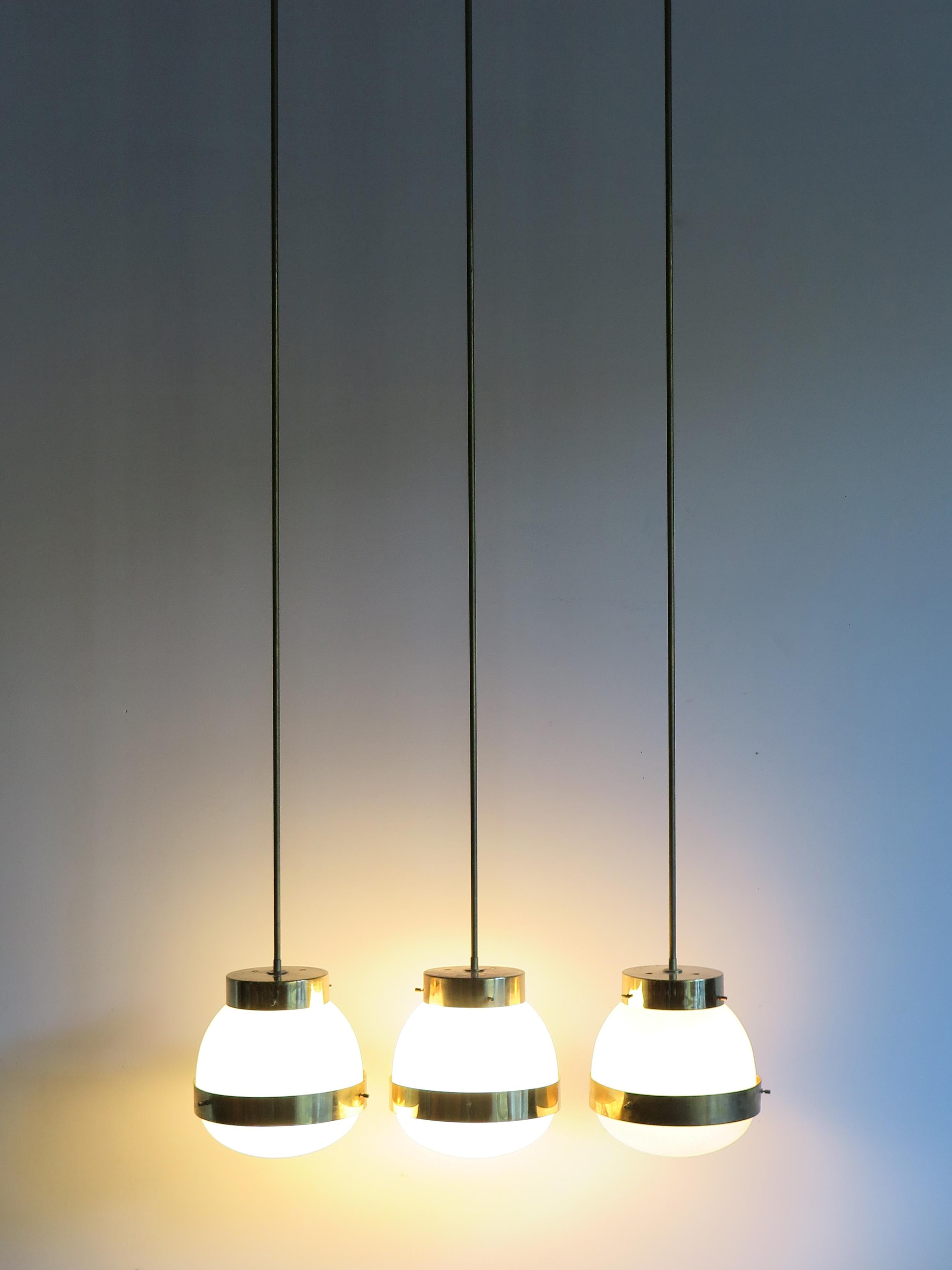 ?Set of three Italian Mid-Century Modern design pendant lamps model Delta designed by Sergio Mazza and produced by Artemide with brass, opaline glass and pressed glass; the stem has been replaced and can be shortened on request, Italy