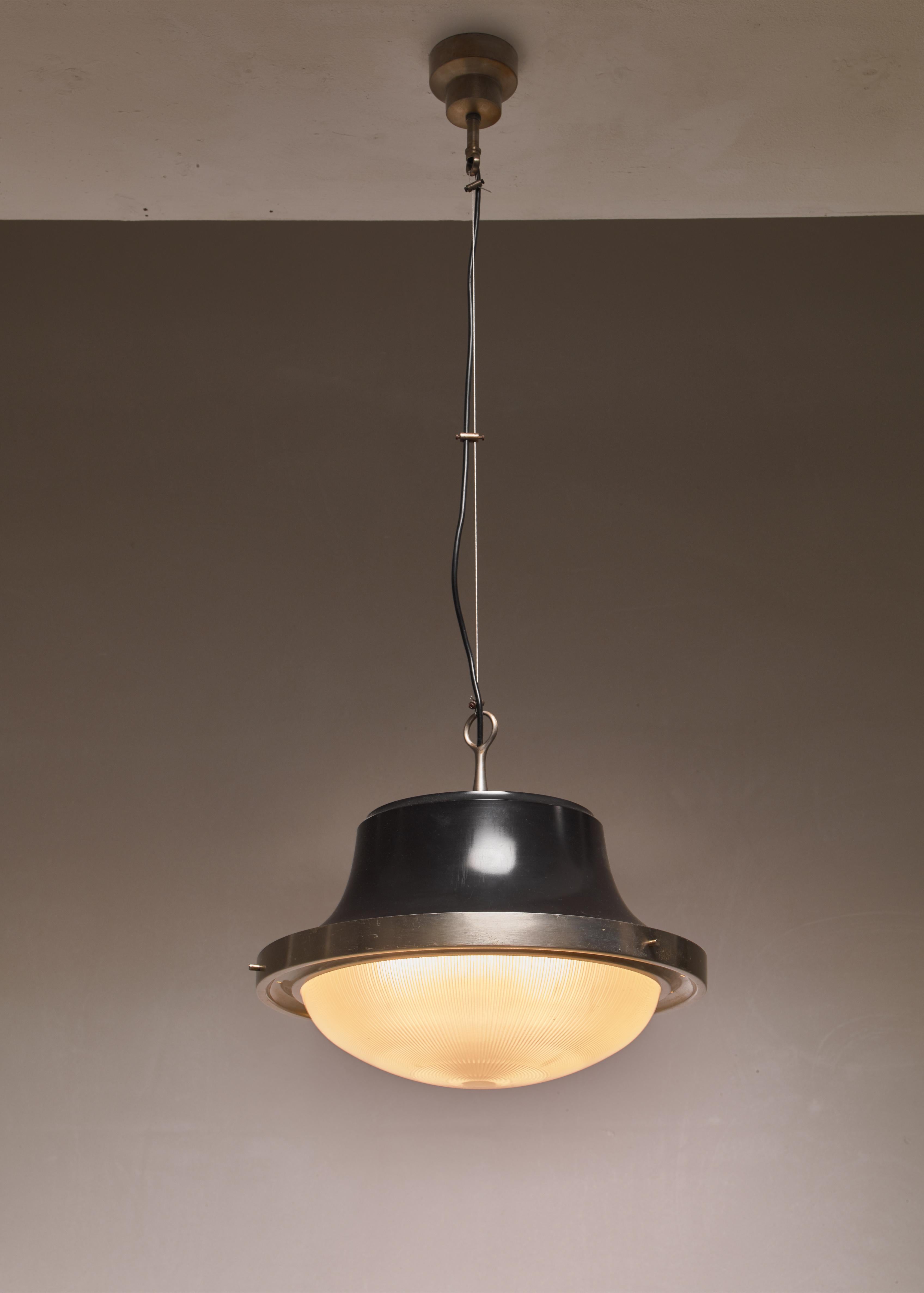 A model 'Tau' pendant lamp by Sergio Mazza for Artemide. The lamp has a black lacquered aluminum shade with a nickel plated brass ring around and a pressed, striped glass diffuser. It hangs from a metal wire.

The measurements stated are of the