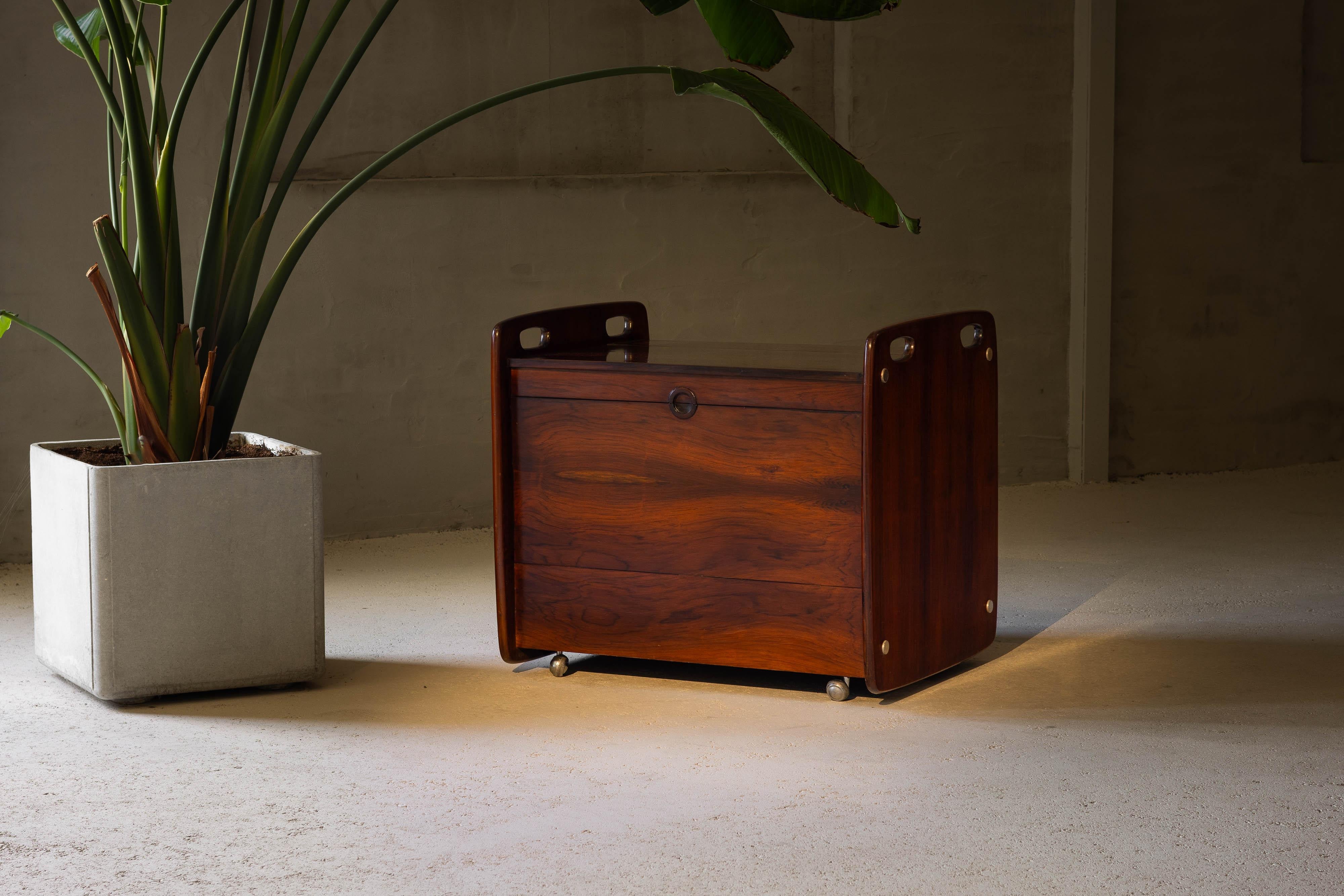 This stunning dry bar cart, designed by Sergio Rodrigues and manufactured by OCA in Brazil in 1965, is a quintessential piece of mid-century modern design. Comprising two folding doors that open the top and front in full to reveal the spacious