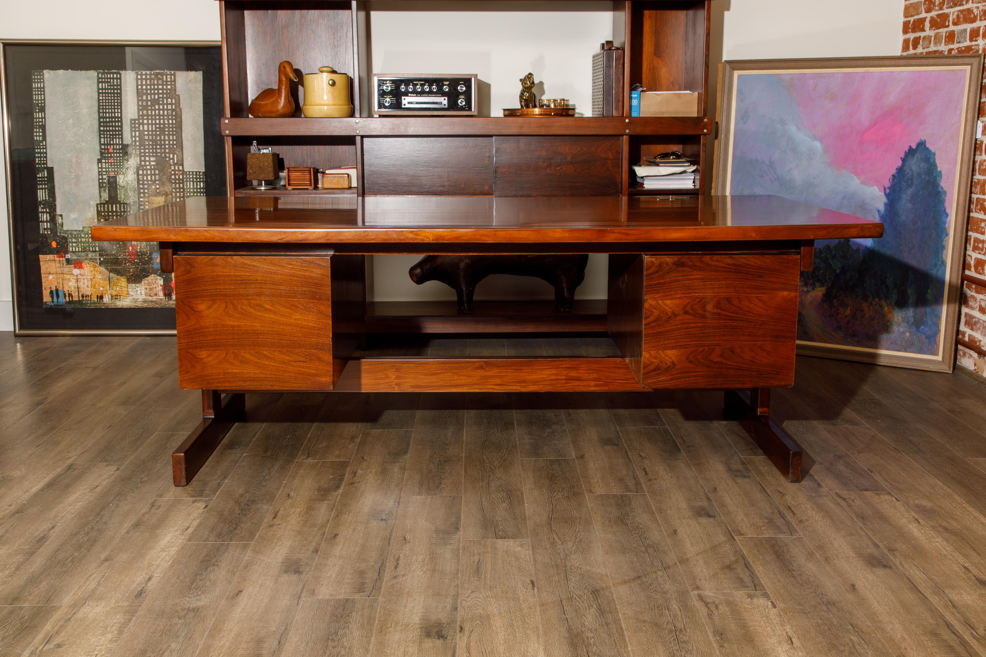 This exotic Brazilian Rosewood 'Clara' executive desk by Sergio Rodrigues, circa 1960s, features beautifully grained Jacaranda Rosewood, signature trestle base with four drawers. The drawer faces on this example favor clean lines showing off the