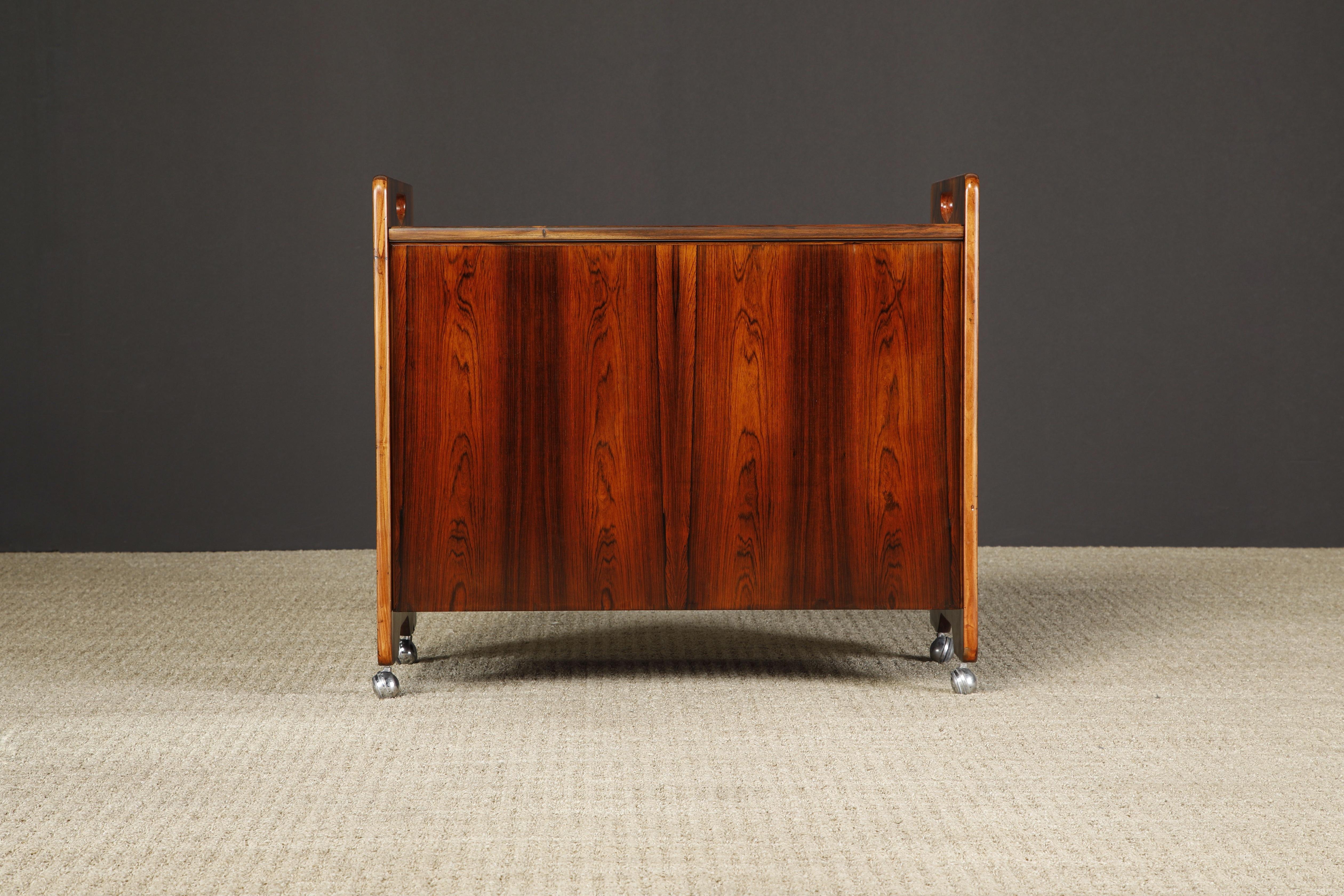 This innovative bar cart by Sergio Rodrigues was crafted in circa 1960 from Brazilian Rosewood with contrasting white formica interior, made in Brazil and recently imported to the states. Fully restored and ready to be used and cherished