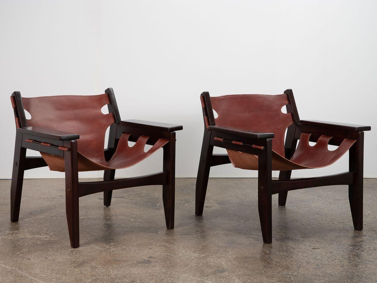 Striking pair of Brazilian modern leather sling chairs, designed by Sergio Rodrigues for his own company OCA. Inspired by hammocks widely used in the tropical climate, the chairs have an angular, minimal frame that support relaxed saddle leather