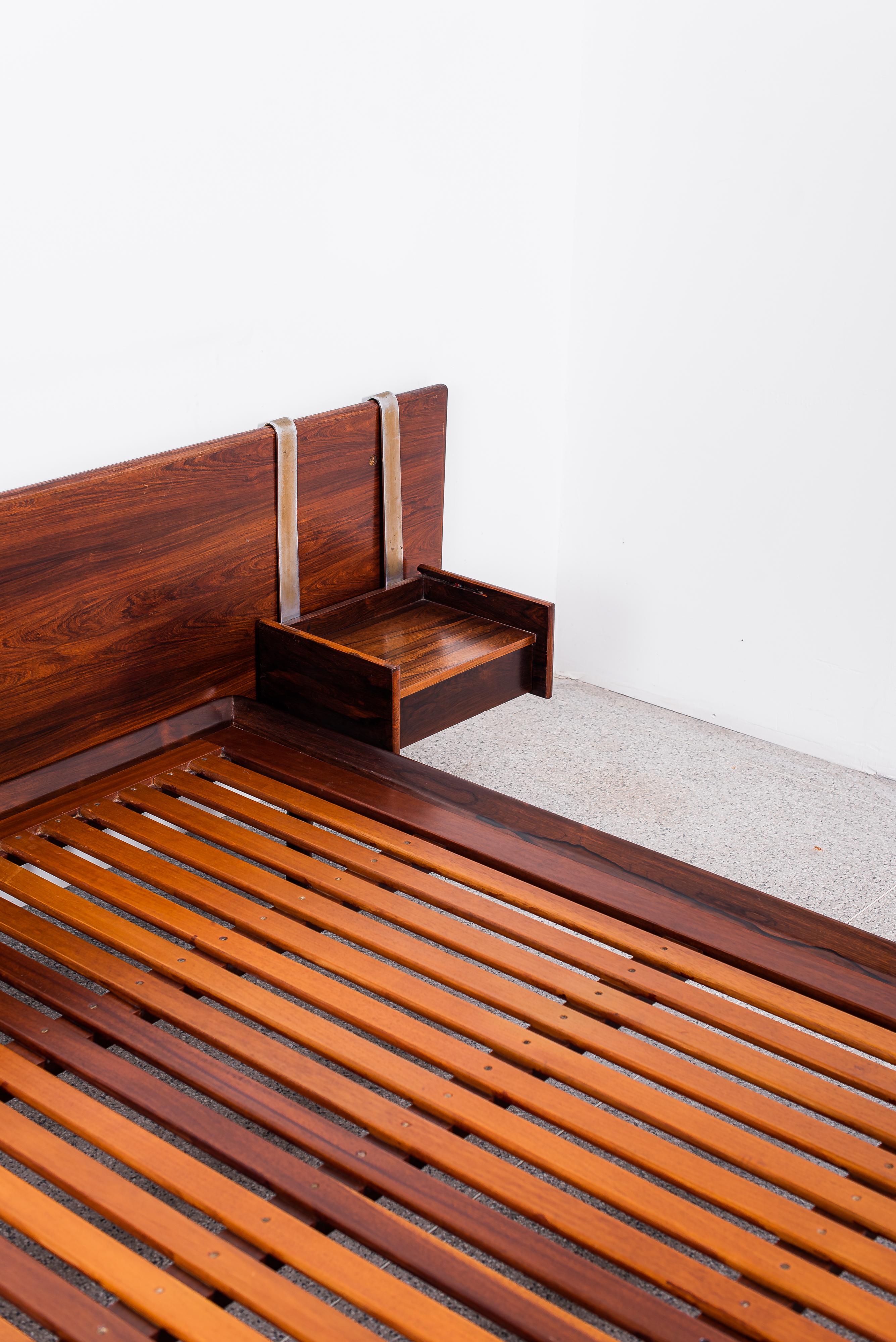 Sergio Rodrigues' Luxor Set is a sleek, minimalist daybed designed in 1965. Known for its clean lines and elegant simplicity, the set features a slatted wooden frame with cylindrical feet. The frame is typically made of high-quality wood like