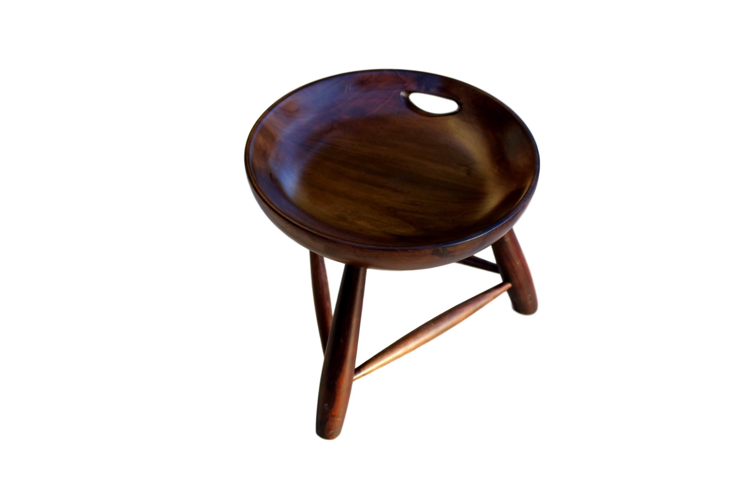 Mid-Century Modern 'Mocho' stool in hardwood by Brazilian designer Sergio Rodrigues. Each with concave seat and handle, on turned bulbous form legs with spreader bars. Good vintage condition, consistent with age and use.

P.S. Colors may