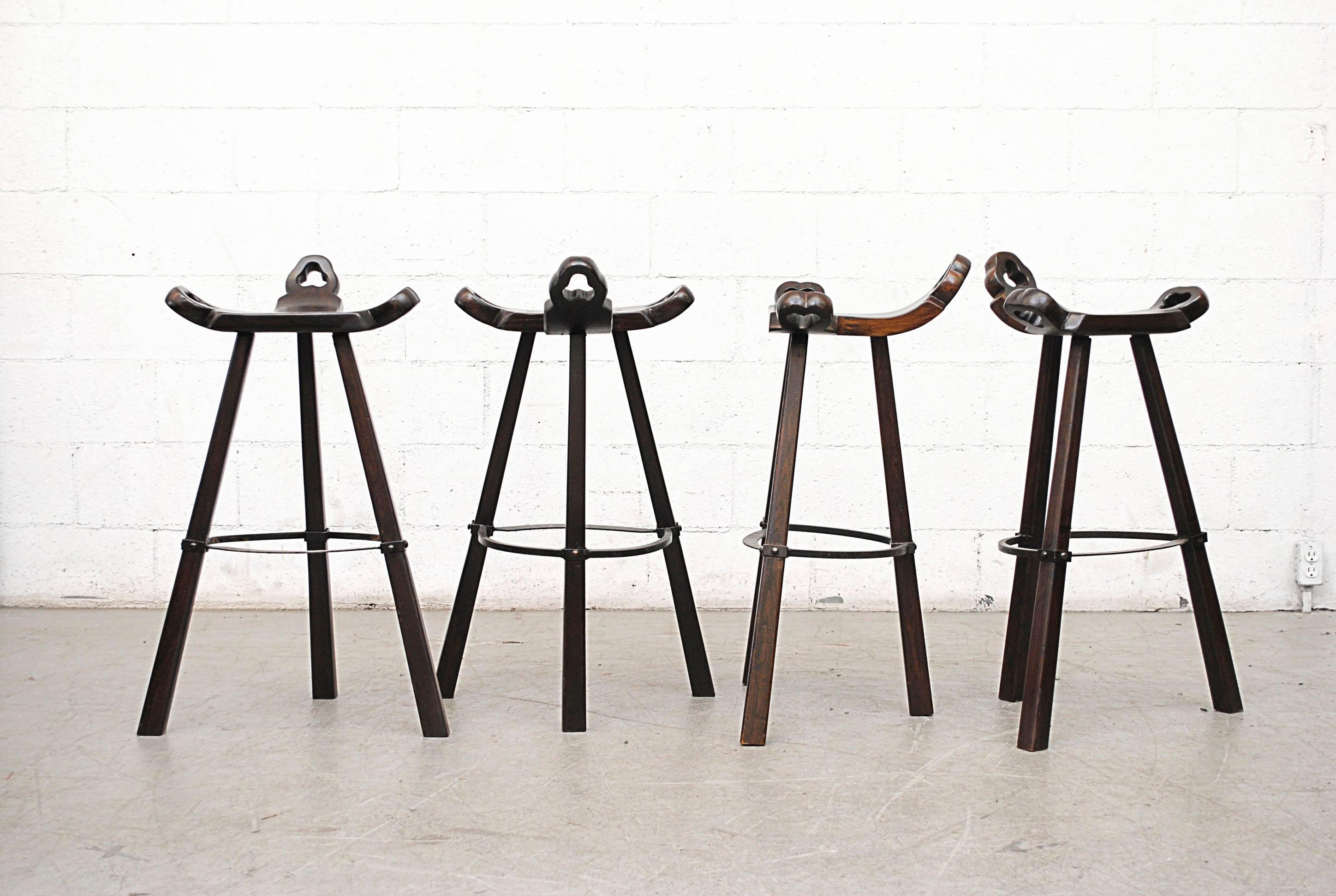 Lightly refinished Brutalist hand-carved dark oak Sergio Rodriguez style Spanish bars stools with black steel patterned footrests. Arabic influence.