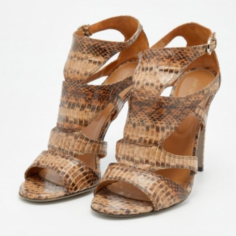 Ti innamorerai sicuramente di questo paio di sandali di Sergio Rossi. Questi sandali con cinturino sono realizzati in pelle di serpente esotica e sono disponibili in beige. Sono rifinite con suole robuste e tacchi di 12 cm e sono le scarpe perfette