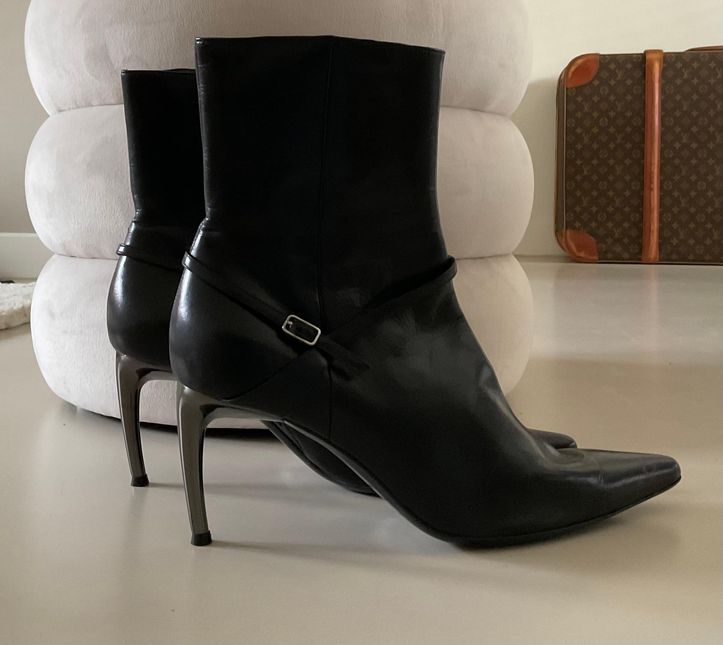 Ces exceptionnelles bottines en cuir noir Sergio Rossi sont une pièce rare et exquise, confectionnées dans un cuir noir souple et dotées d'une bride de cheville raffinée qui ajoute une touche de sophistication intemporelle. Le design est rehaussé