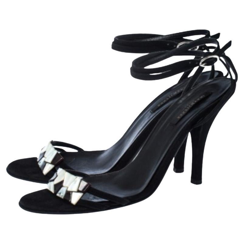 Setzen Sie mit diesen modischen Sandalen von Sergio Rossi ein modisches Statement. Diese schwarzen Sandalen sind aus Wildleder gefertigt und haben eine offene Zehensilhouette. Sie zeigen sich mit Perlmuttverzierungen an den Riemen des Vorderteils