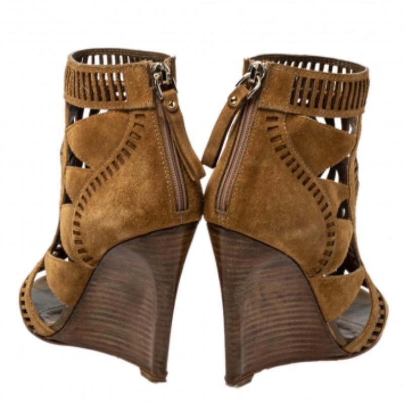 Add the Sergio Rossi charm to your shoe collection with this pair of ankle booties. Crafted using brown suede, the booties feature open toes, back zippers, and laser-cut detailing all over. They are lifted on wedge heels.