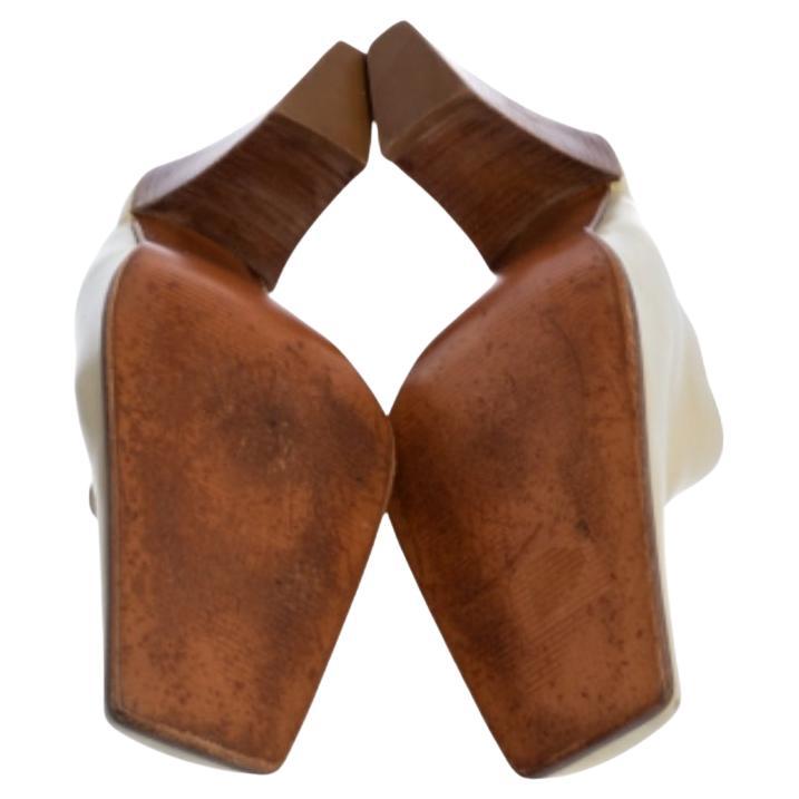 These fashionable mules from Sergio Rossi are crafted with leather. This pair features covered, square toes, comfortable insoles, and block heels. These cream mules offer both elegance and comfort.