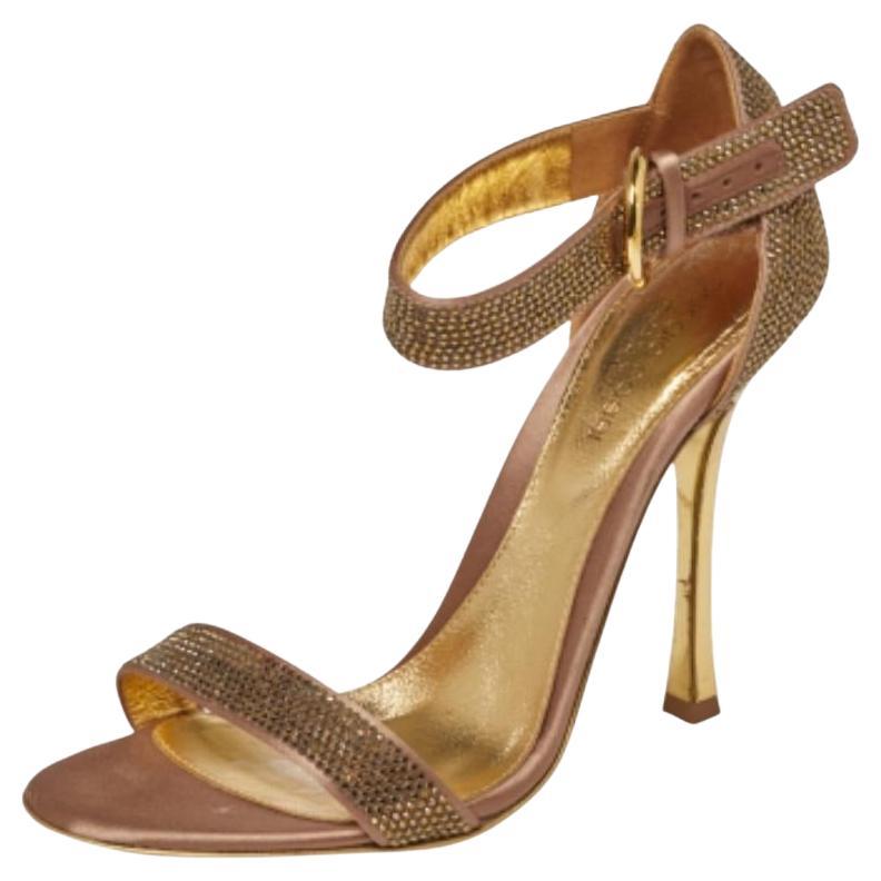 Es gibt nichts, was wir an diesen Sandalen von Sergio Rossi nicht lieben würden! Sie beeindrucken uns mit ihrer goldenen Satin-Konstruktion und den exquisiten Kristallverzierungen. Sie haben eine zehenoffene Silhouette, einzelne Riemen am