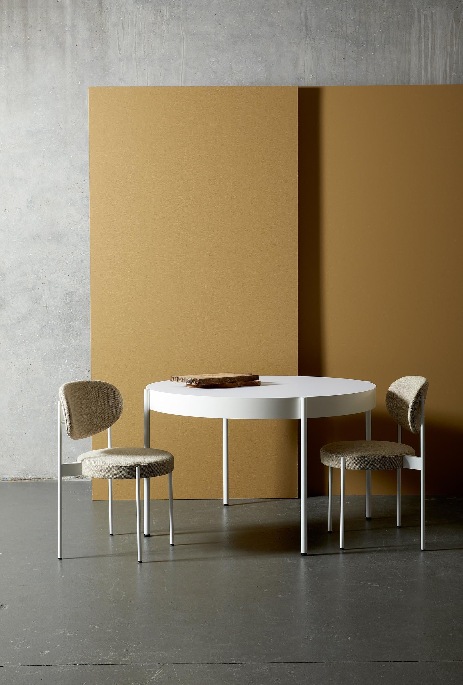 Round dining table with obvious frame. Legs placed outside the frame of the table designed by Verner Panton.

Material:
Frame: Black or white painted metal legs
White: RAL 9016 
Edge: Painted MDF
Table top: Fenix laminate 

Color:
Tabletop: