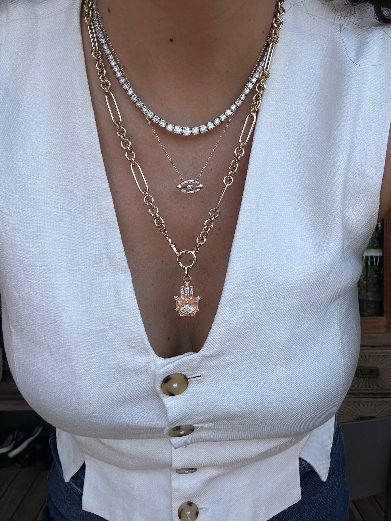 Este elegante collar de oro presenta un cautivador colgante inspirado en un ojo maligno, adornado con brillantes diamantes. El centro luce un delicado diamante en forma de marquesa, rodeado de un halo de piedras brillantes redondas. Suspendida de
