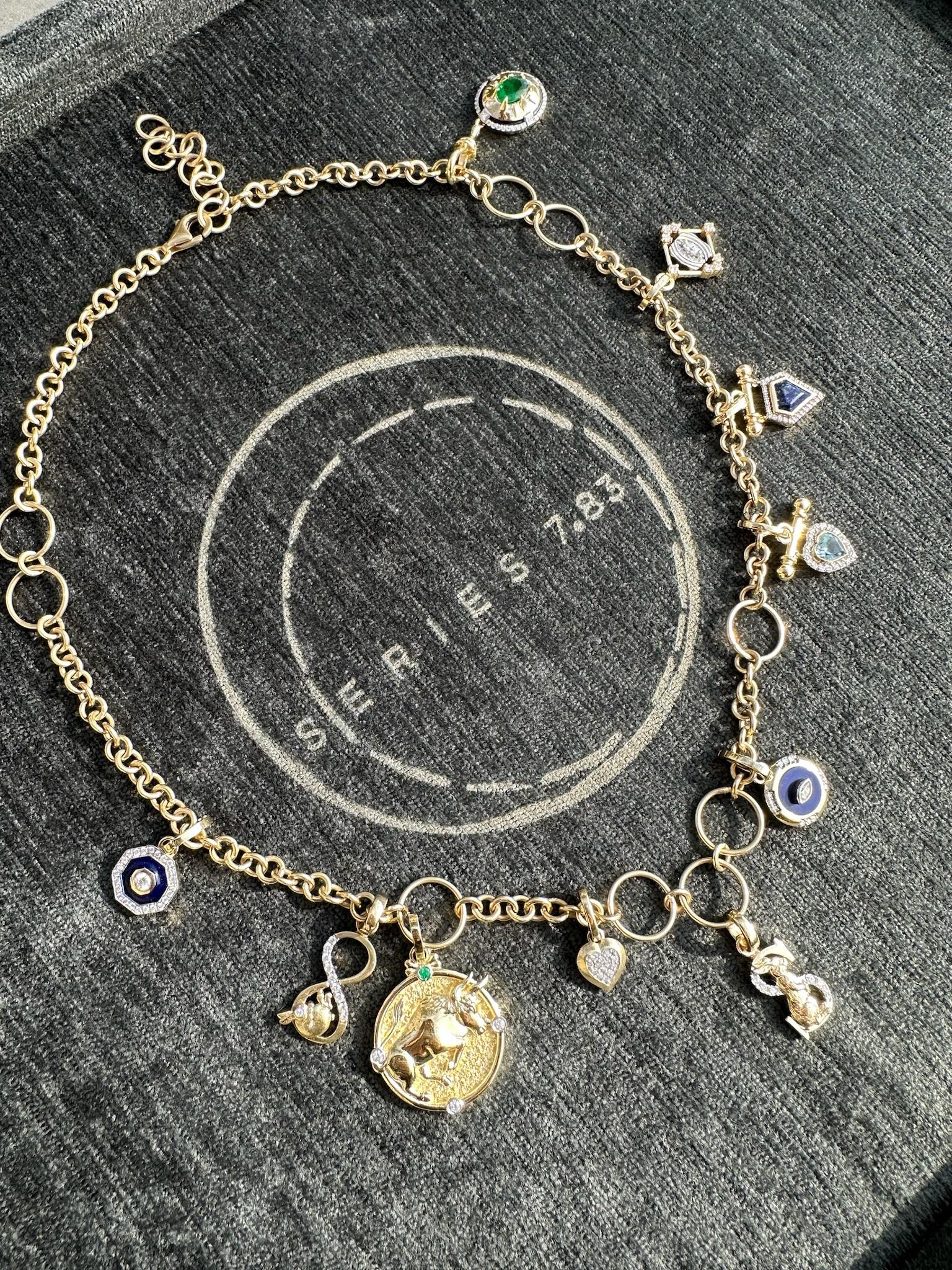 This elegant 14K gold chain features a timeless link design, adorned with delicate hoops that add texture and character. Versatile and stylish, it can be worn on its own for a refined, minimalist look or personalized by adding a range of charms to
