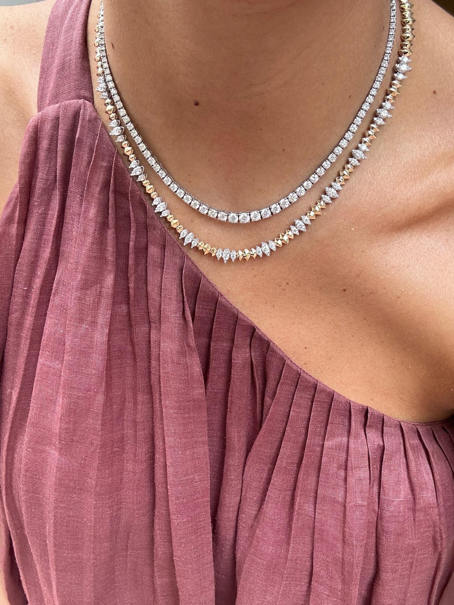 This sophisticated necklace features a unique combination of yellow gold and shimmering diamond accents. The design comprises geometric, faceted gold links that gracefully encircle the neck, interrupted by clusters of round, pavé-set diamonds for a