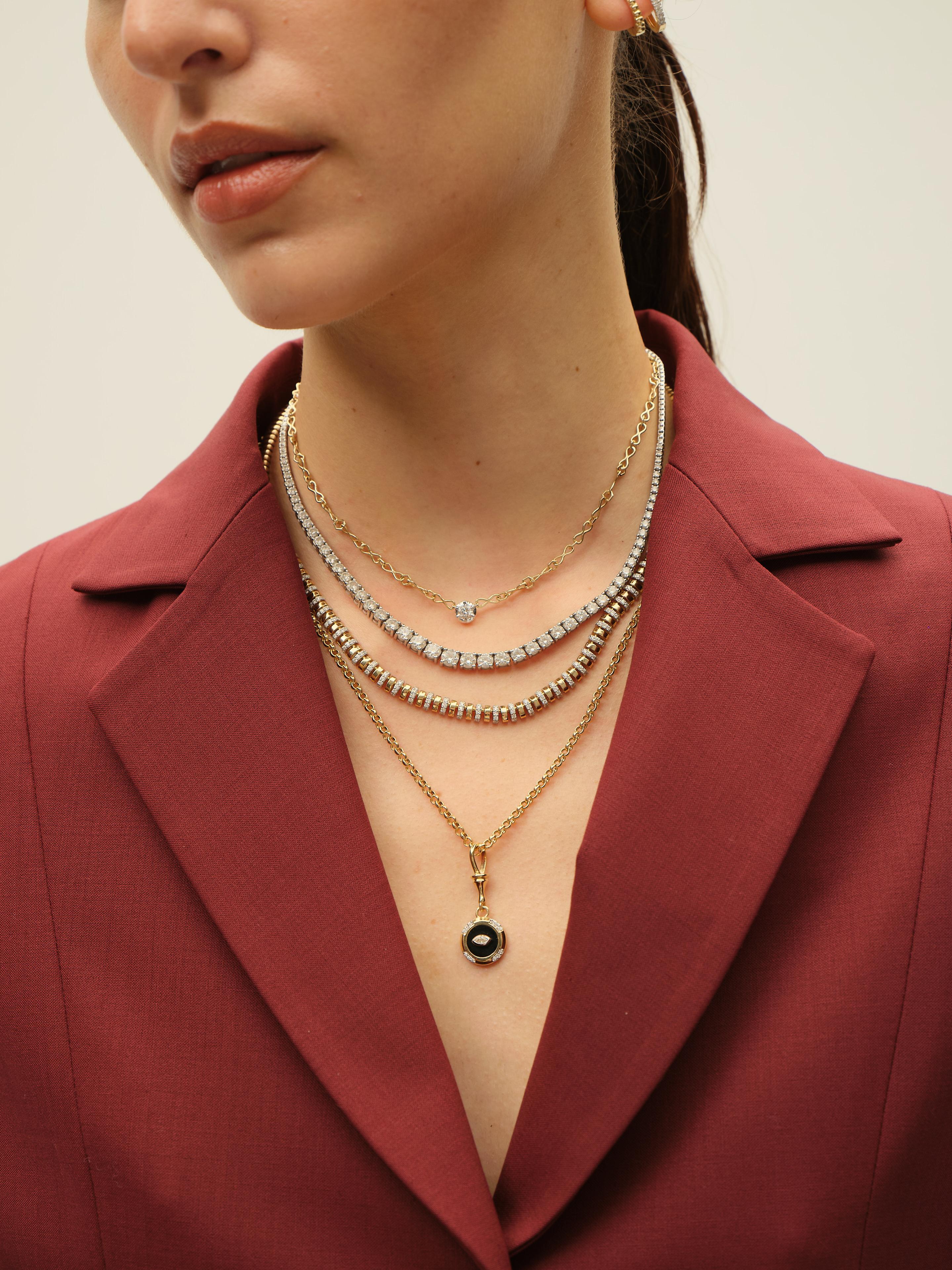 This elegant necklace features a sophisticated two-tone design crafted from yellow gold and adorned with shimmering diamonds. The piece comprises a flexible row of polished gold links, subtly interrupted by segments set with round diamonds for a