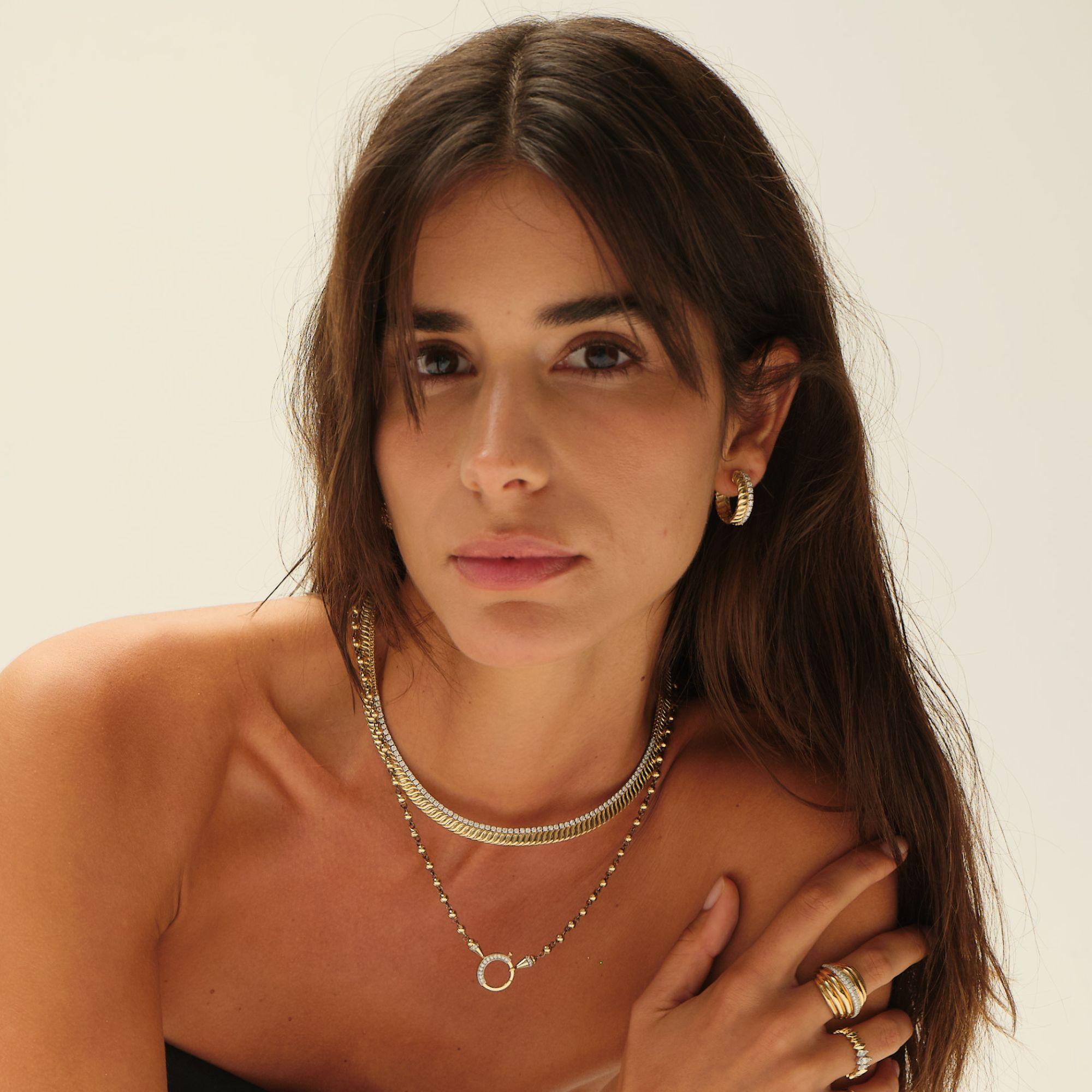 This elegant necklace blends the classic sophistication of a tennis necklace with a bold, contemporary twist. Crafted in rich 14 K yellow gold, it features a sleek row of brilliant-cut diamonds gracefully set into a ribbed design, creating a