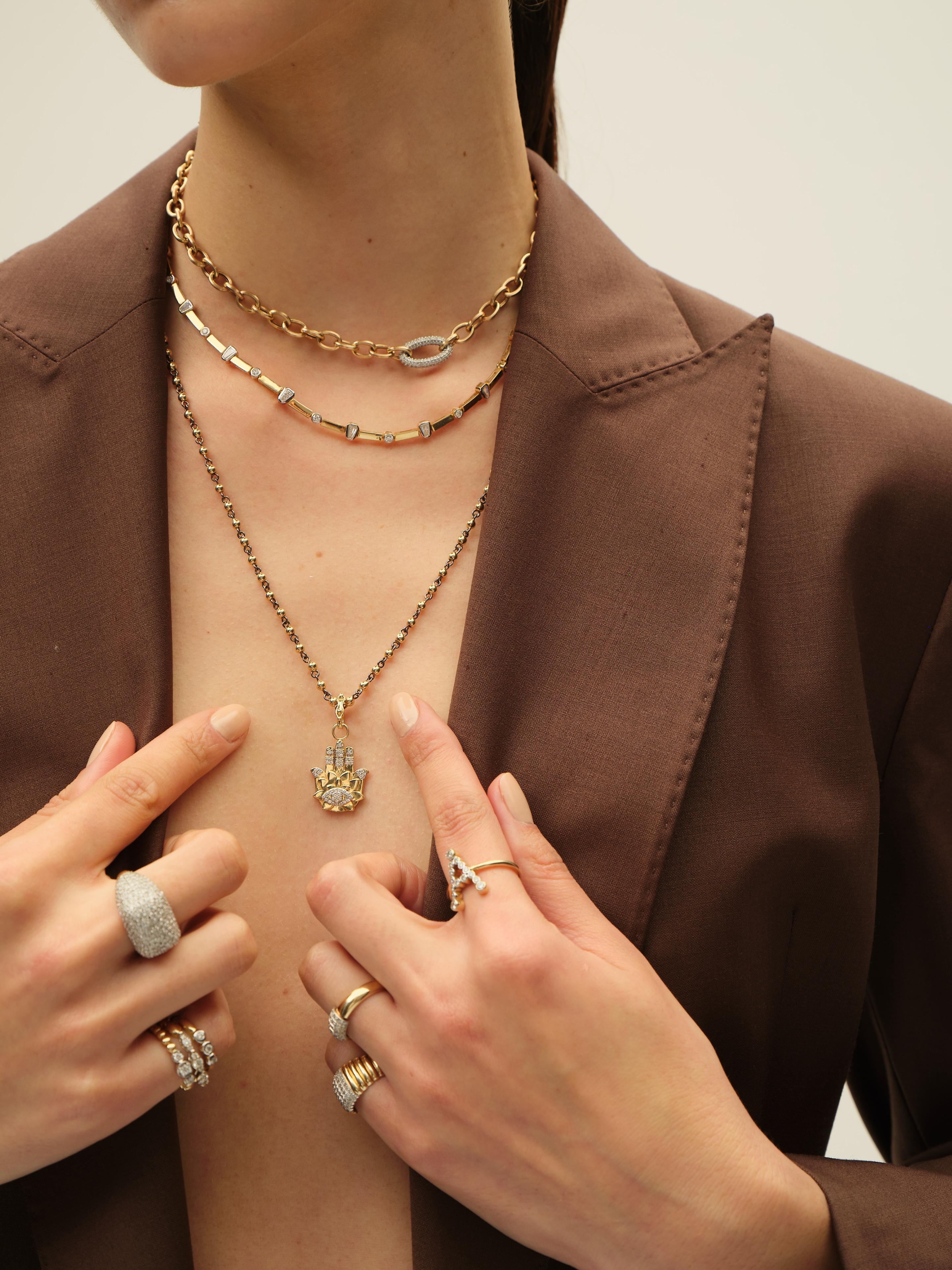 This modern 14K yellow gold necklace features an artistic mix of polished gold links and scattered diamond-accented elements. With a playful yet refined arrangement of bezel-set diamonds and textured white gold details, it offers a contemporary