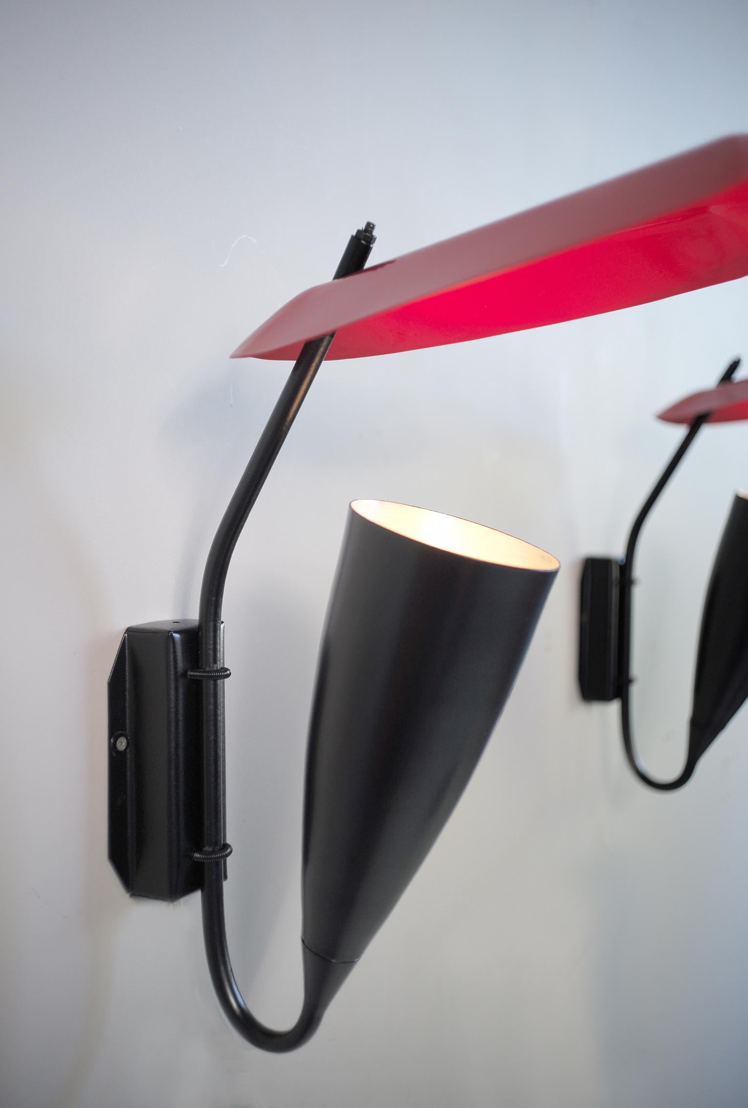 Large wall lamp in black and red lacquered metal, France, 1950. In the tradition of designers such as Jacques Biny, Michel Buffet or Robert Mathieu, this architect's creation uses indirect light, reflected by a large bent sheet metal deflector and