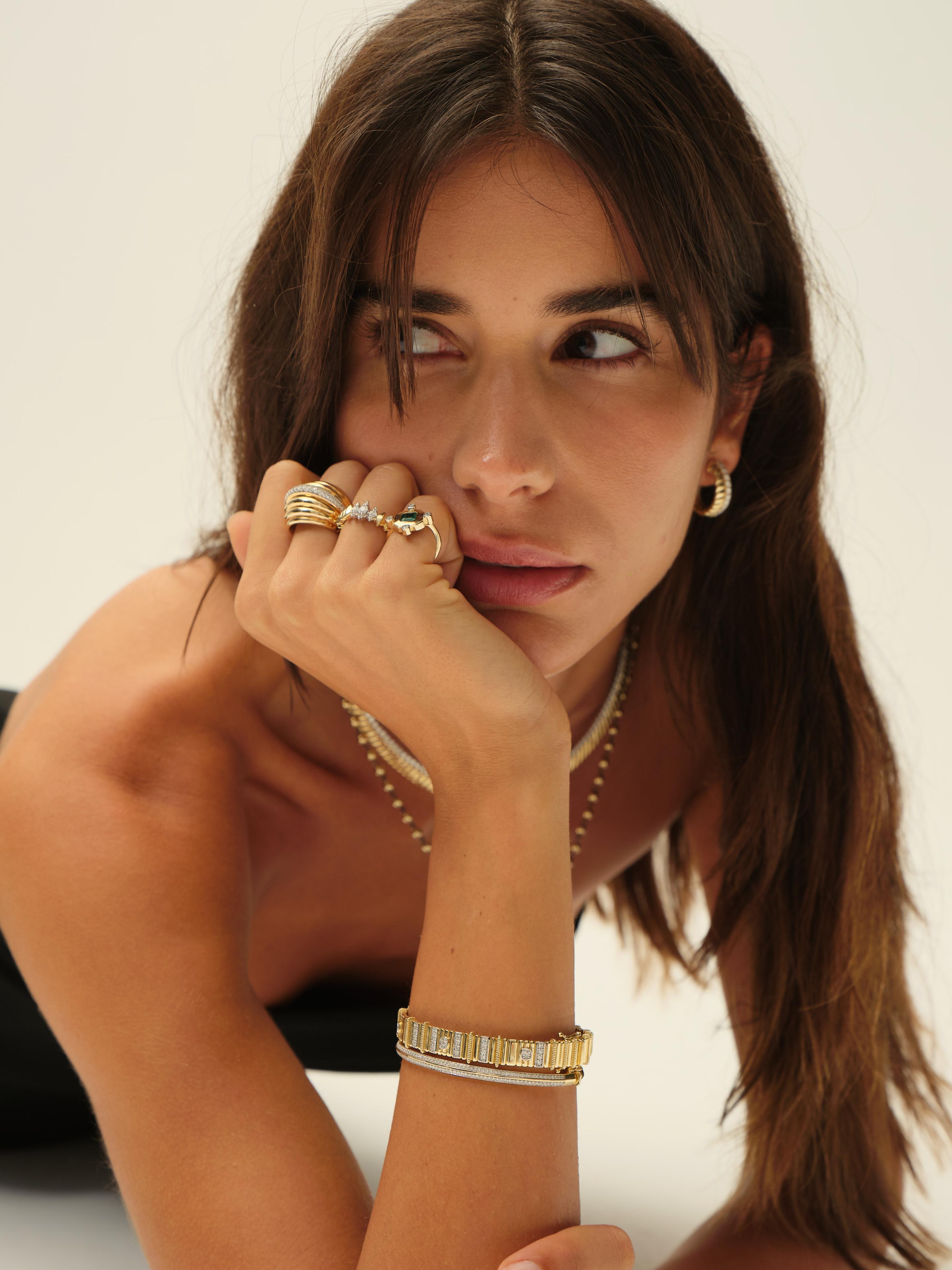 Este lujoso brazalete de oro muestra un refinado diseño geométrico con segmentos de diamantes en pavé y estriados alternados. Acentuado con diamantes redondos engastados en bisel, combina a la perfección textura y brillo. El interior presenta un