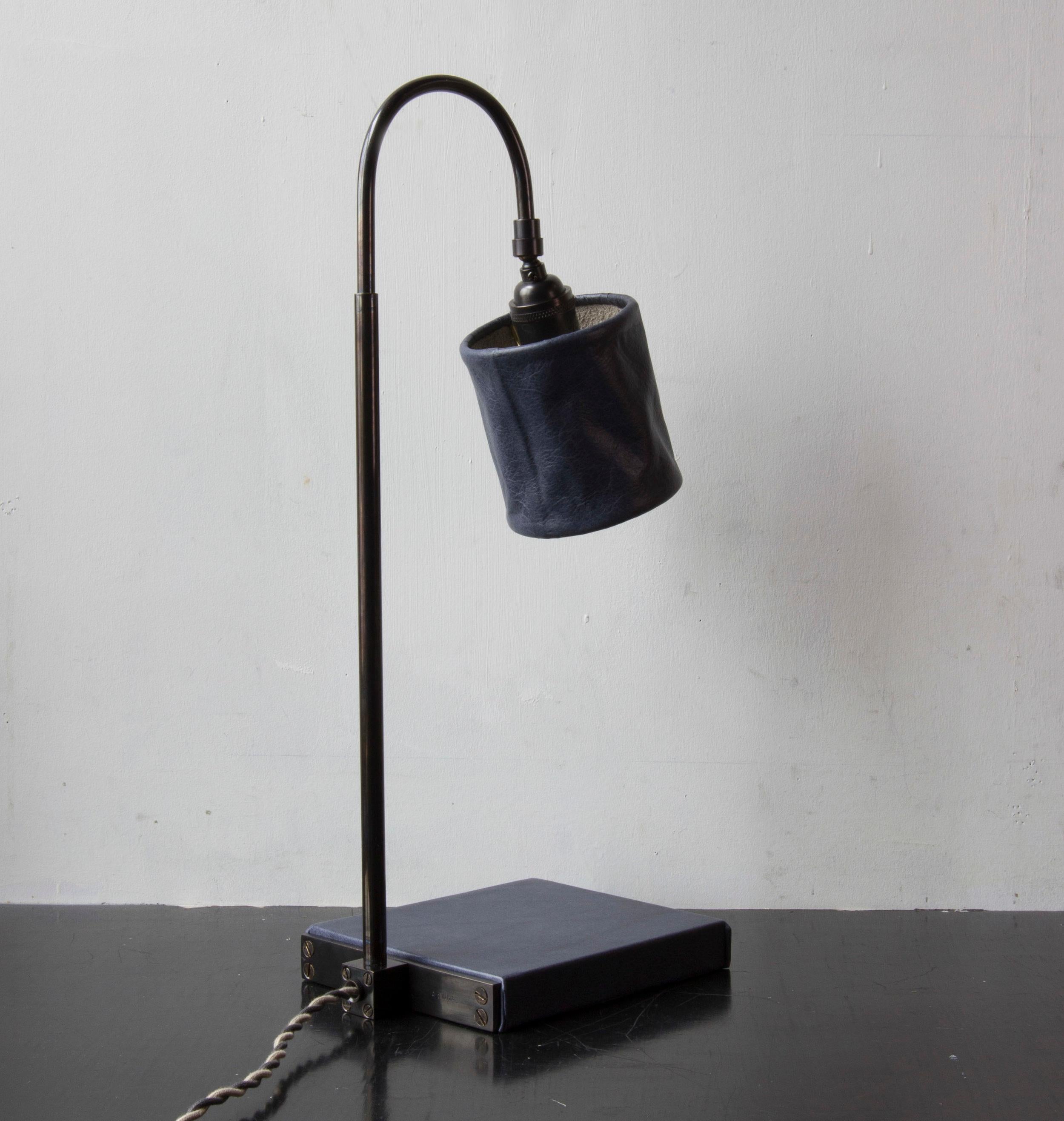 Solid machined brass in dark patinated brass finish, hand-dyed and waxed leather wrapped wood, soft unstructured pivoting leather shade, hand-dyed braided cotton cord. All material finishes are living finishes: they will change and patina for the
