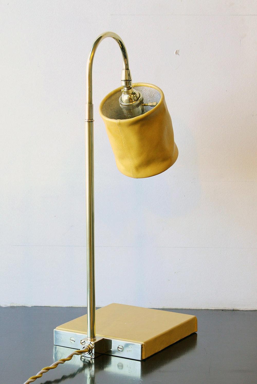 Solid machined brass in polished un-lacquered finish, hand-dyed and waxed leather wrapped wood, soft unstructured pivoting leather shade, hand-dyed braided cotton cord. All material finishes are living finishes: they will change and patina for the