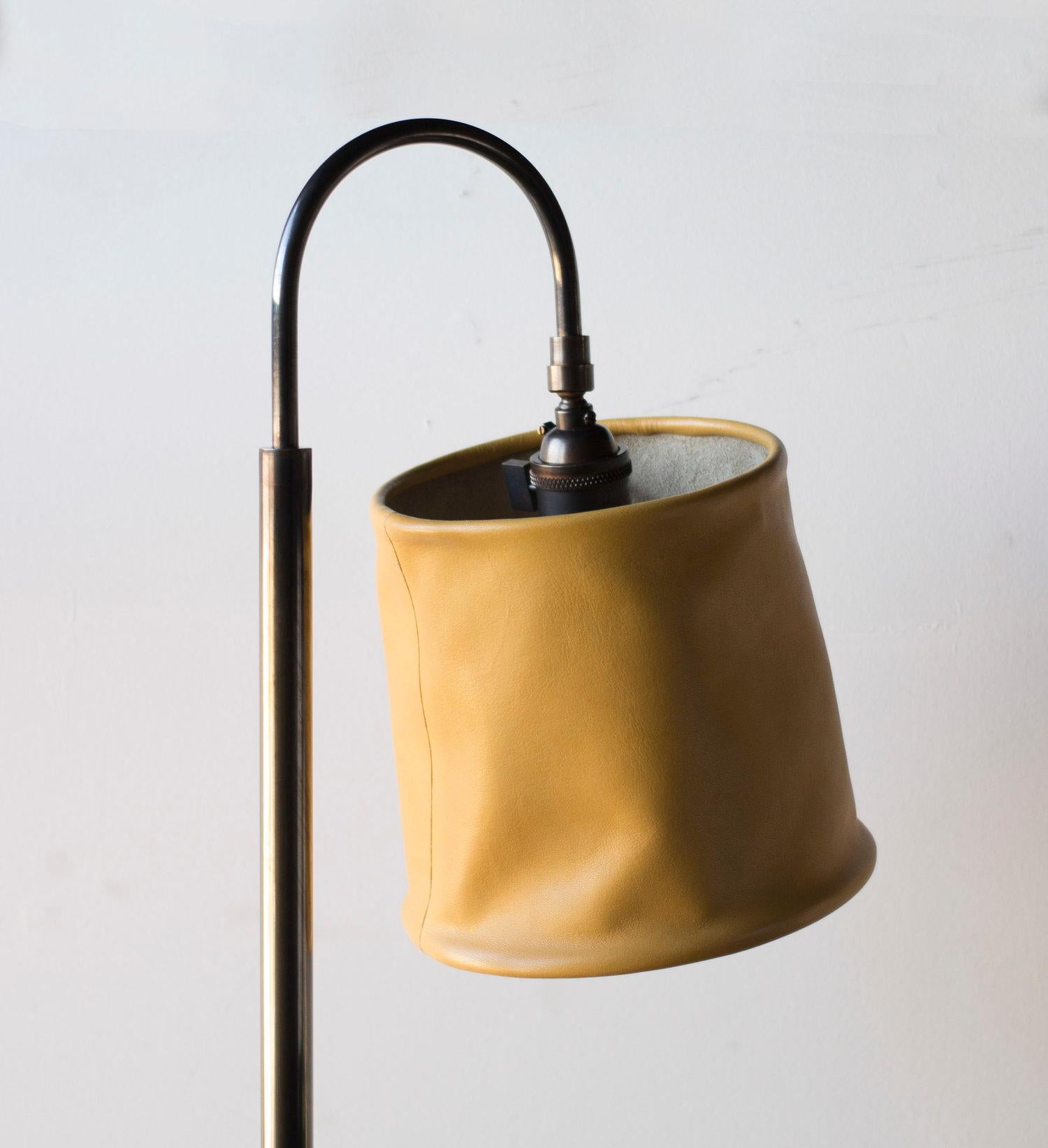 Solid machined brass in dark patinated brass finish, hand-dyed and waxed leather wrapped wood, soft unstructured pivoting leather shade, hand-dyed braided cotton cord. All material finishes are living finishes: they will change and patina for the