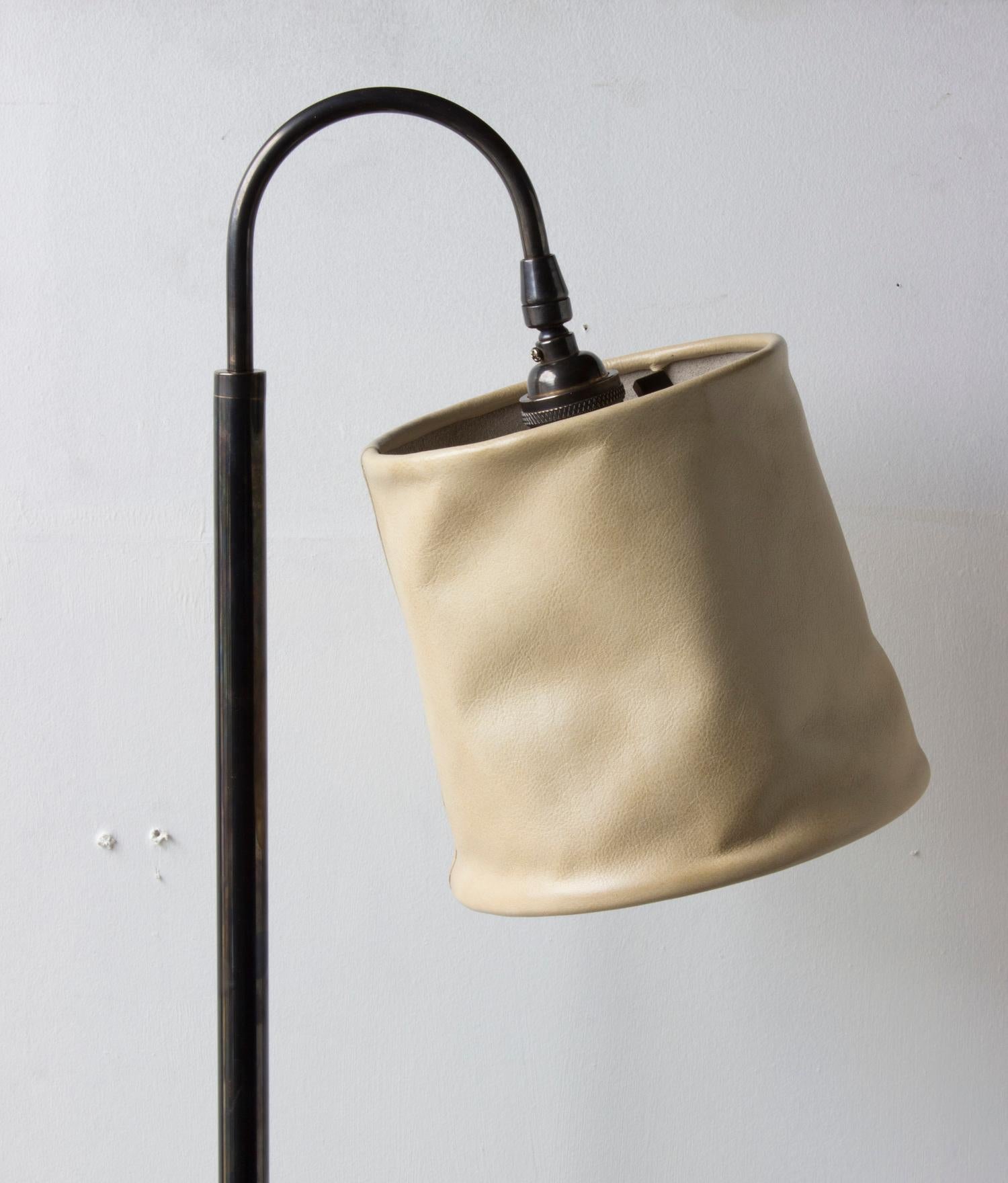 Solid machined brass in dark patinated brass finish, hand-dyed and waxed leather wrapped wood, soft unstructured pivoting leather shade, hand-dyed braided cotton cord. All material finishes are living finishes: they will change and patina for the