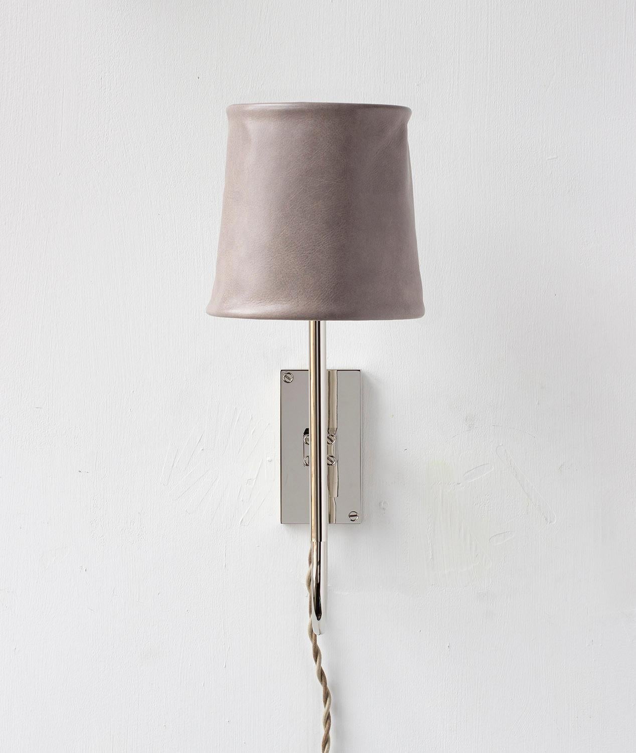 Solid machined brass in polished nickel plated finish, hand-dyed soft unstructured leather shade. All material finishes are living finishes: they will change and patina for the better with time and use. Shown with cord and plug with inline cord