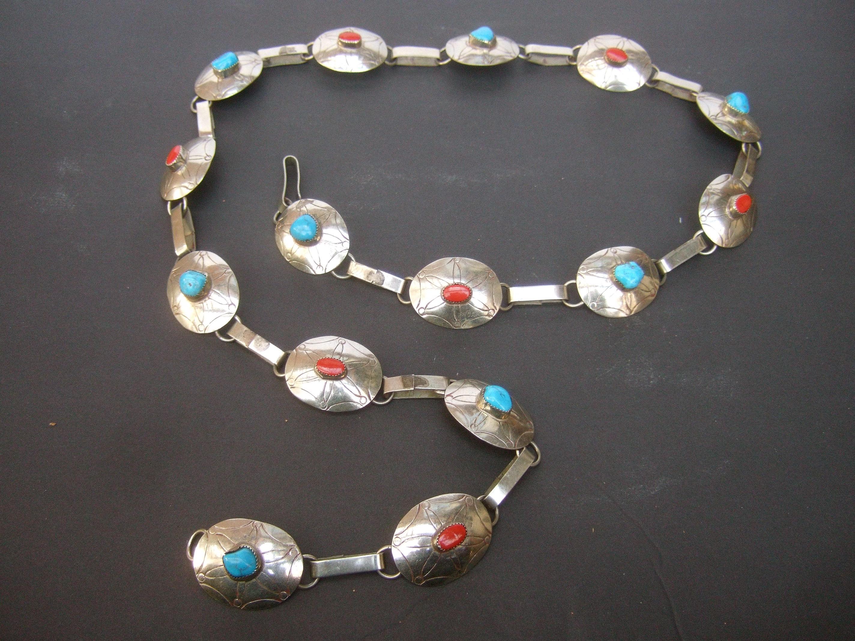 Sterling silver handmade artisan turquoise & coral stone link belt c 1970s
The unique artisan belt is comprised of 15 sterling silver oval-shaped links
with subtle impressed designs 

Each of the sterling silver buckles is adorned with alternating