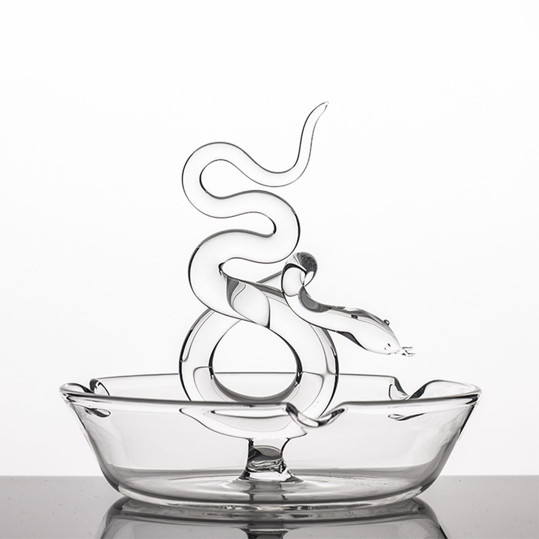 Part of the Serpentine collection, designed by master glassmaker Simone Crestani, this ashtray is inspired by the symbolism and mesmerizing charm of the snake. Handcrafted entirely of glass, it features a round silhouette with two notches at the rim
