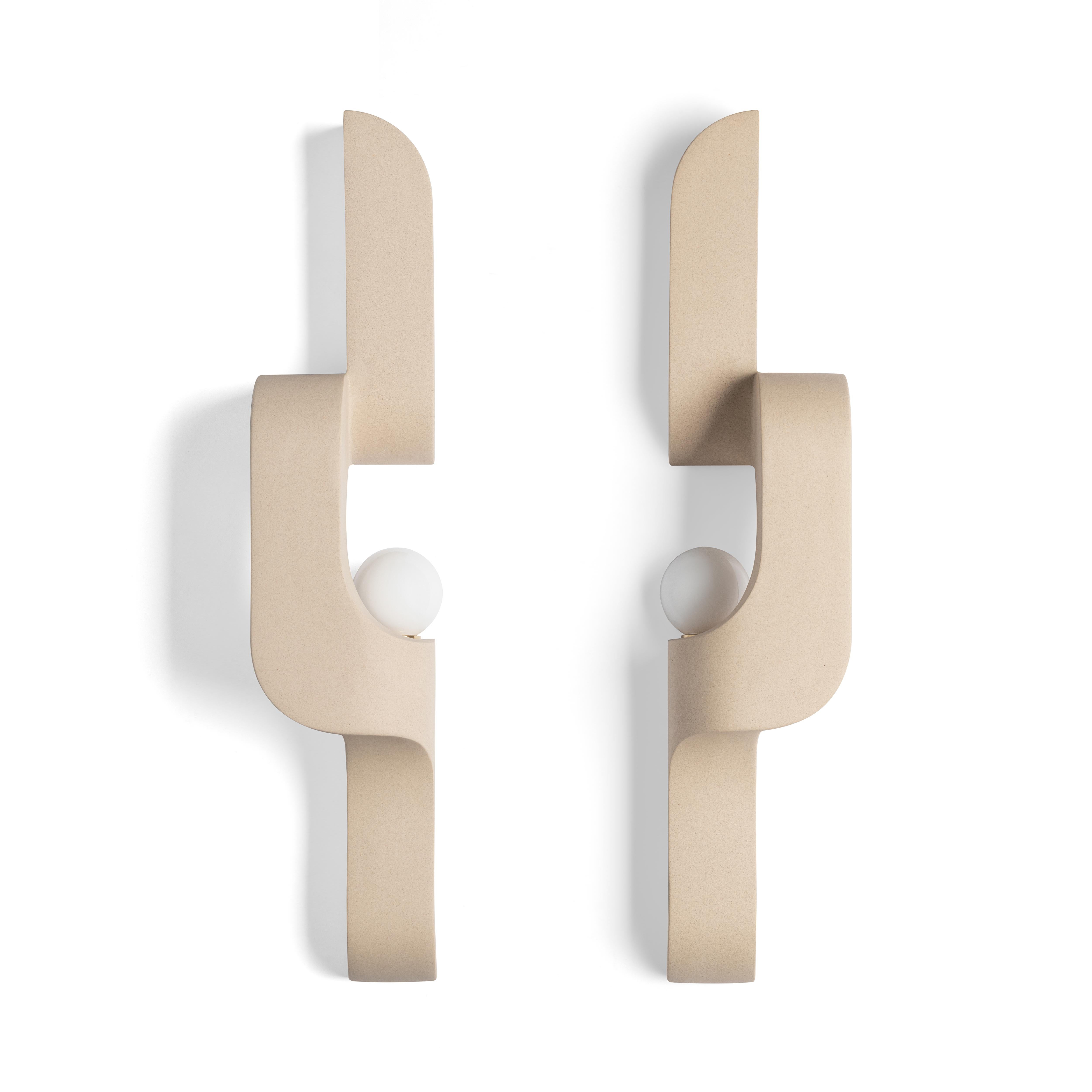 Bei diesem Wandleuchter aus Keramik verbinden sich großzügige Rundungen mit scharfen Kanten und der Wiederholung von Geometrien zu einem Fluss. Der Wandleuchter schlängelt sich an der Wand empor und ist ein skulpturales Beleuchtungselement, das
